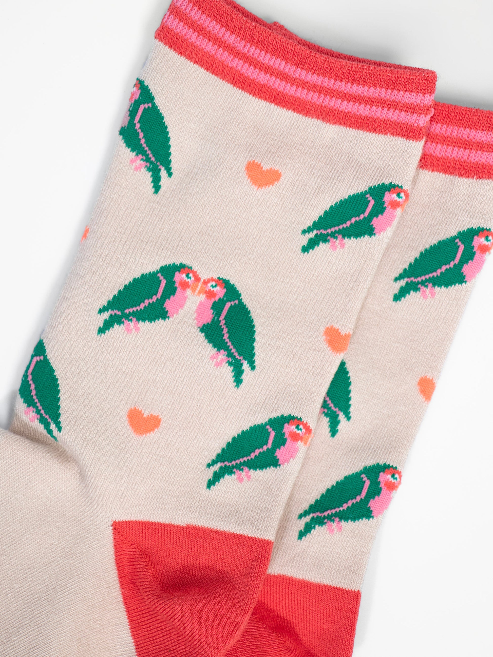close up of the love bird and heart pattern, the love birds are green with pink bellies and beaks, they are in pairs and leaning in together like they are kissing. the love hearts are a pale peach pink colour