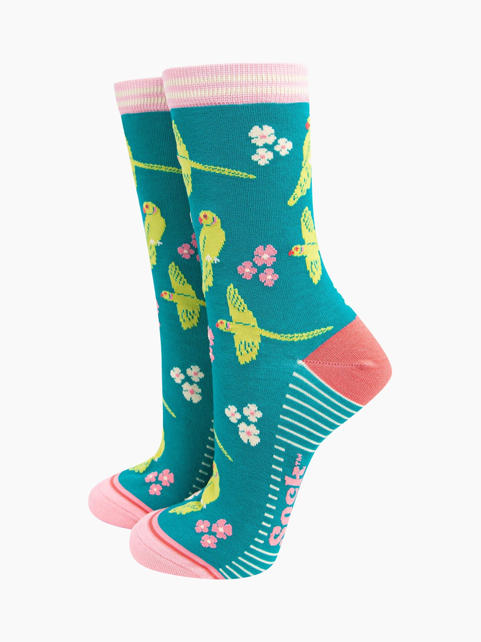 teal bamboo socks with a pattern of flying and perching ring necked parakeets and flowers. the heel and toe are a light coral pink, the cuff is pink and white striped.