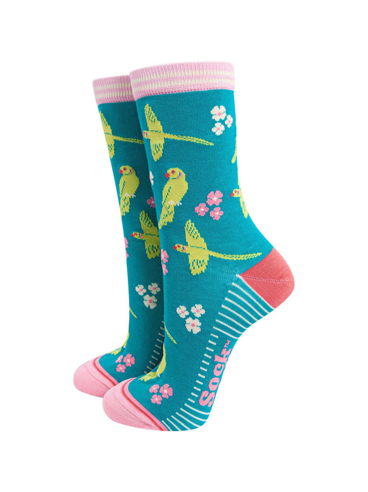 teal bamboo socks with a pattern of flying and perching ring necked parakeets and flowers. the heel and toe are a light coral pink, the cuff is pink and white striped.