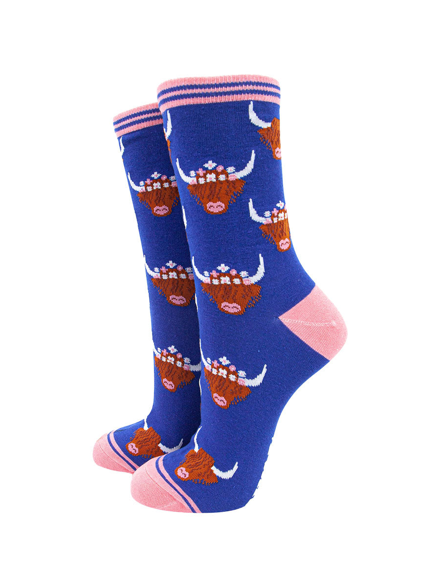 royal blue bamboo socks with pink heel, toe and cuff featuring an all over pattern of highland cows wearing floral crowns