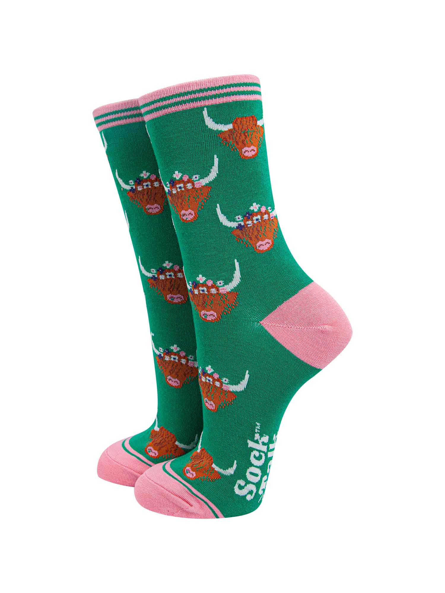 green ankle socks with pink toe, heel and cuff featuring a pattern of brown highland cow faces wearing multicoloured floral wreaths