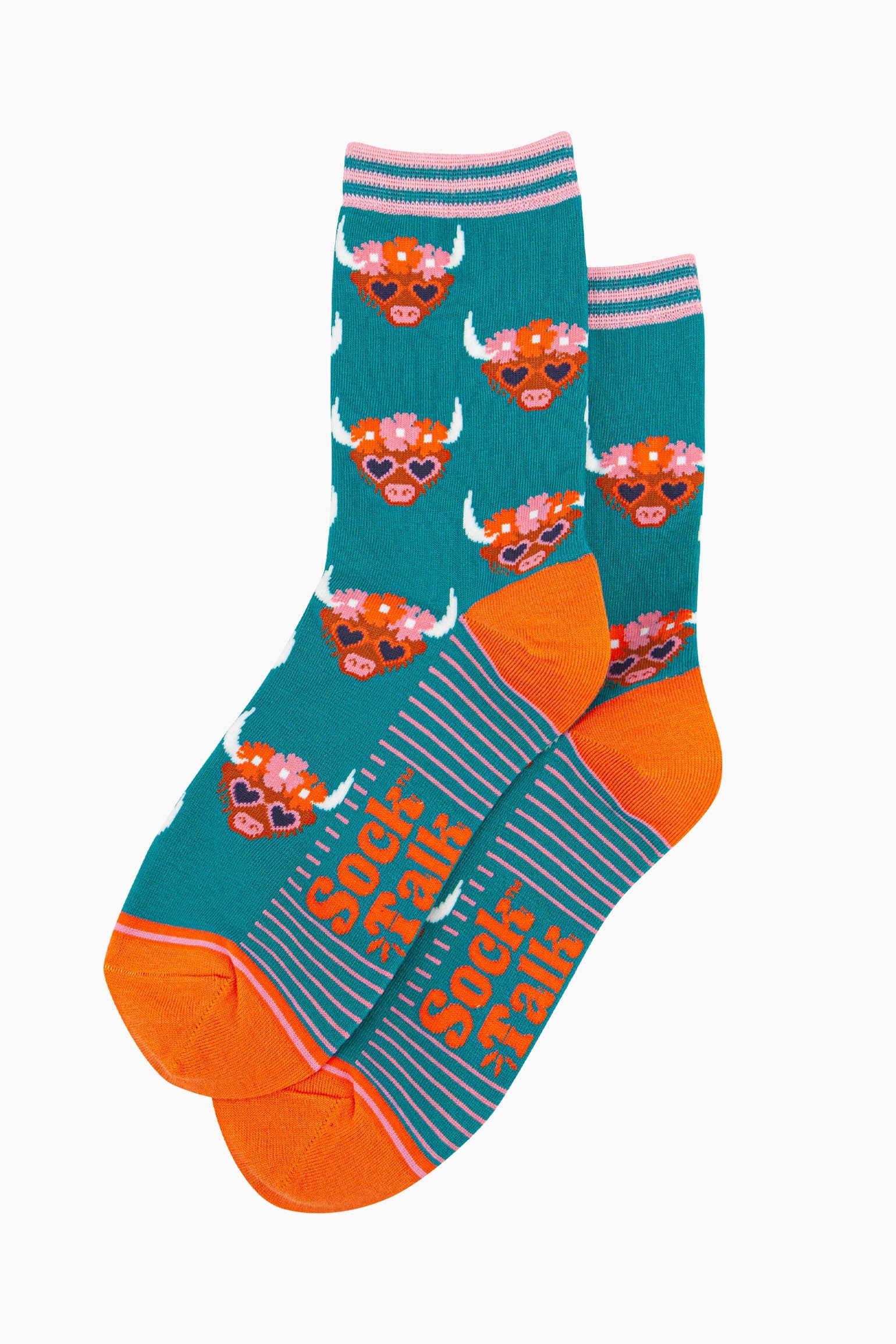 the pair of teal highland cow socks laying flat, one overlapping the other. showing clearly the teal blue background of the socks which is contrasted by the brown highland cow faces. the toe and heel are orange, the sock talk logo is visible on the base of the sole.