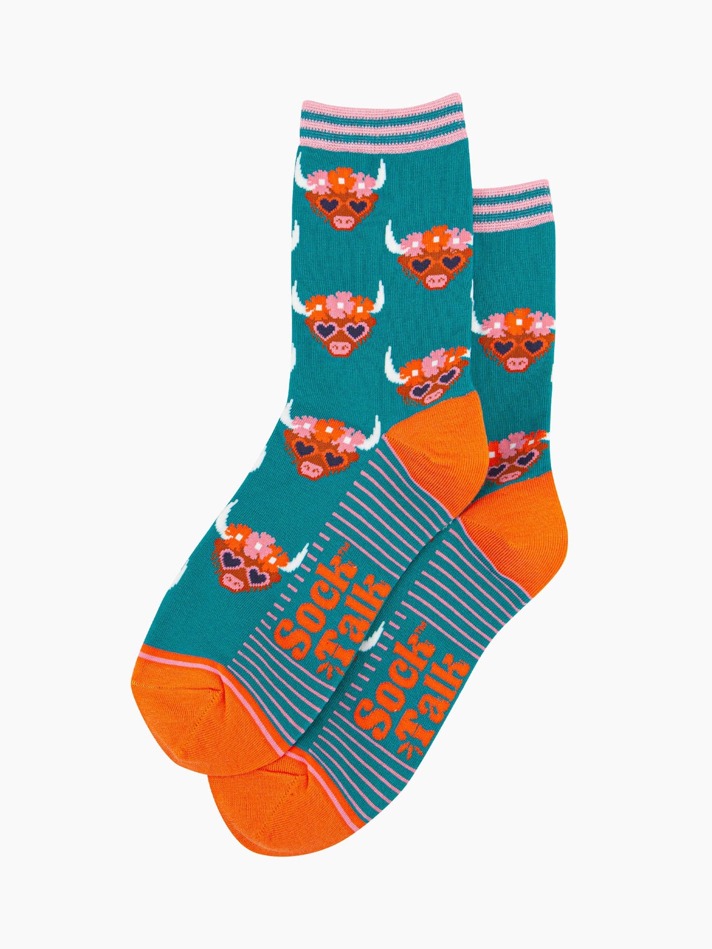 the pair of teal highland cow socks laying flat, one overlapping the other. showing clearly the teal blue background of the socks which is contrasted by the brown highland cow faces. the toe and heel are orange, the sock talk logo is visible on the base of the sole.