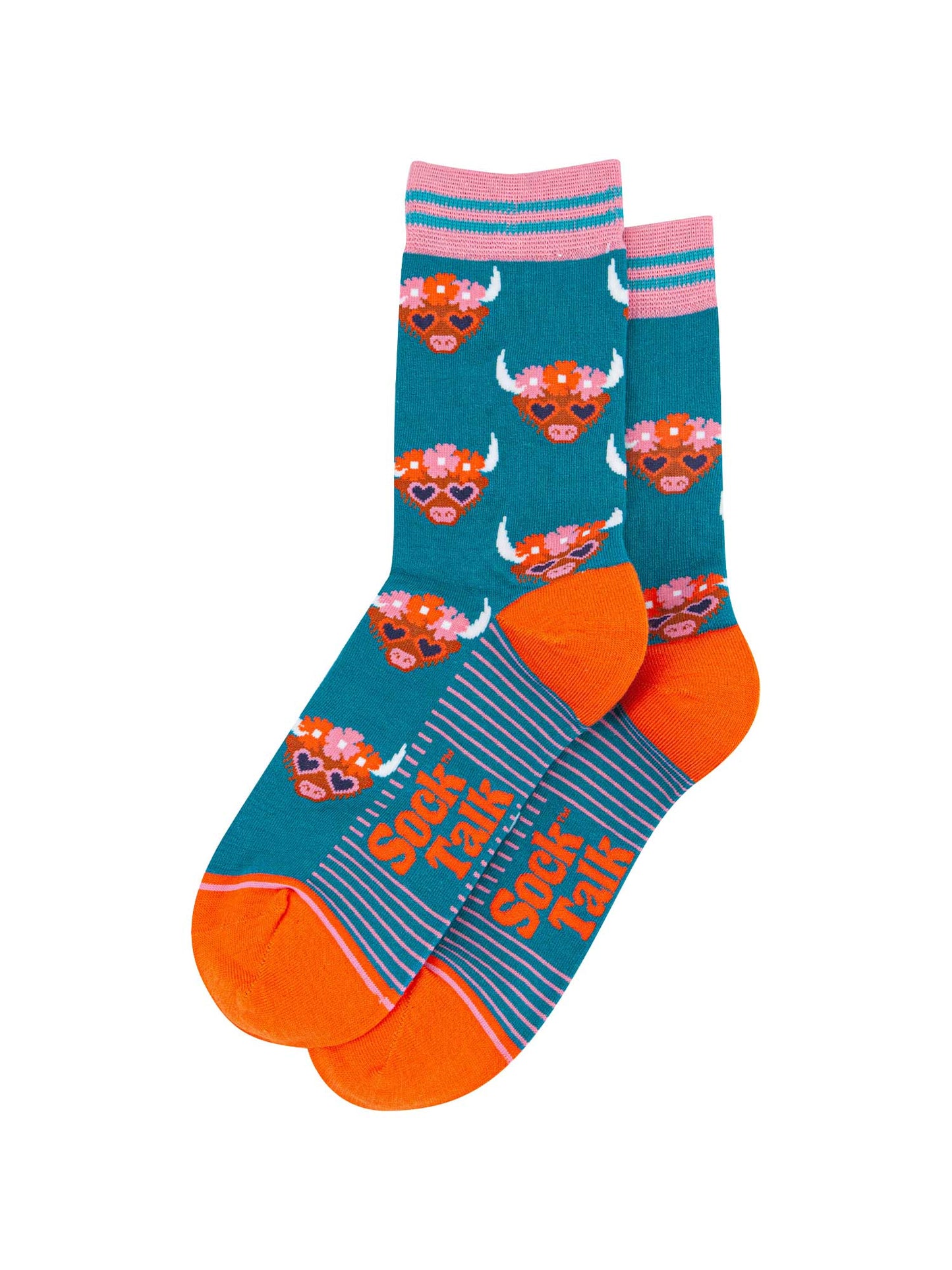 the pair of teal highland cow socks laying flat, one overlapping the other. showing clearly the teal blue background of the socks which is contrasted by the brown highland cow faces. the toe and heel are orange, the sock talk logo is visible on the base of the sole.