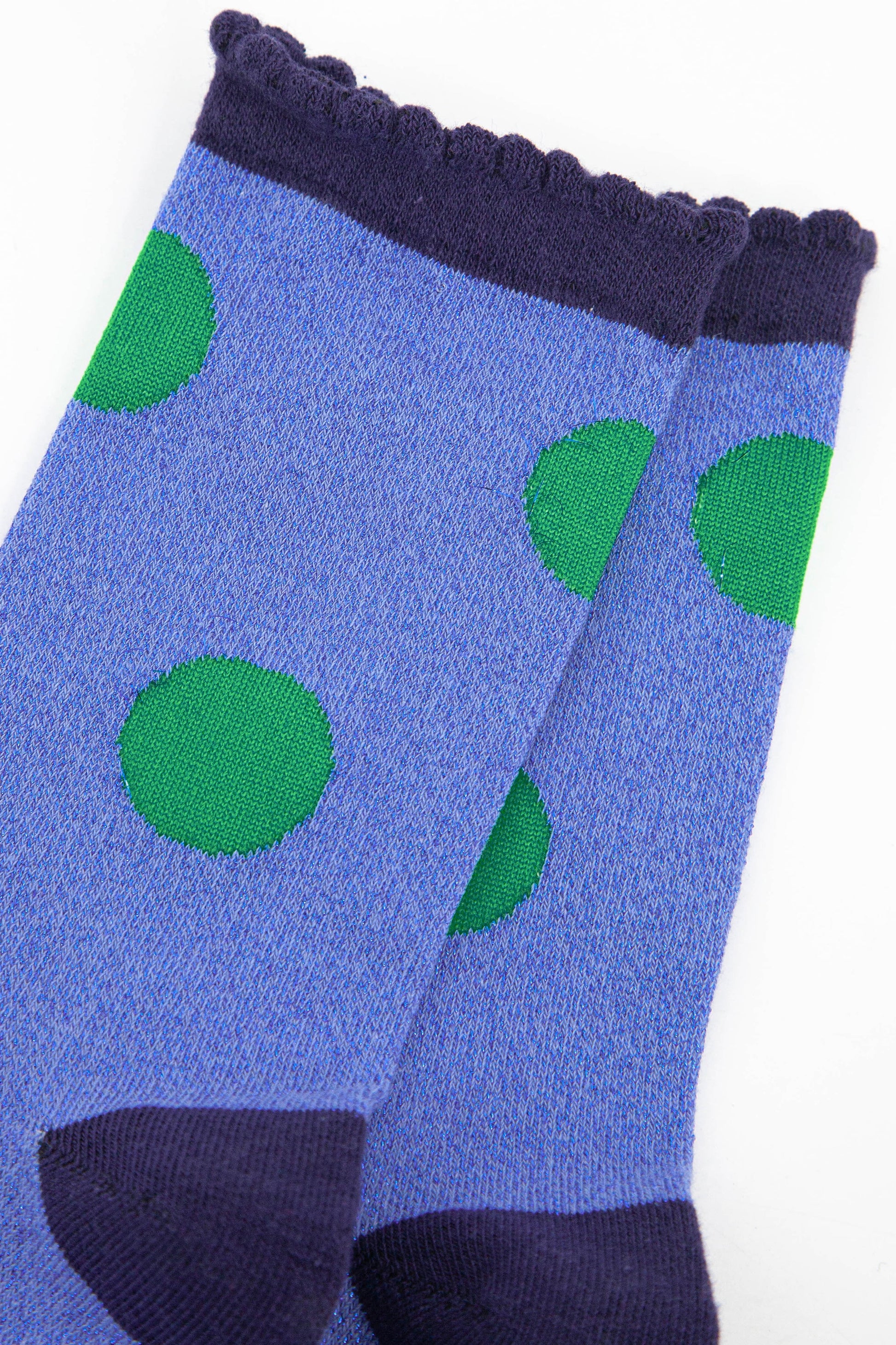 close up of the green polka dot pattern on the denim blue socks