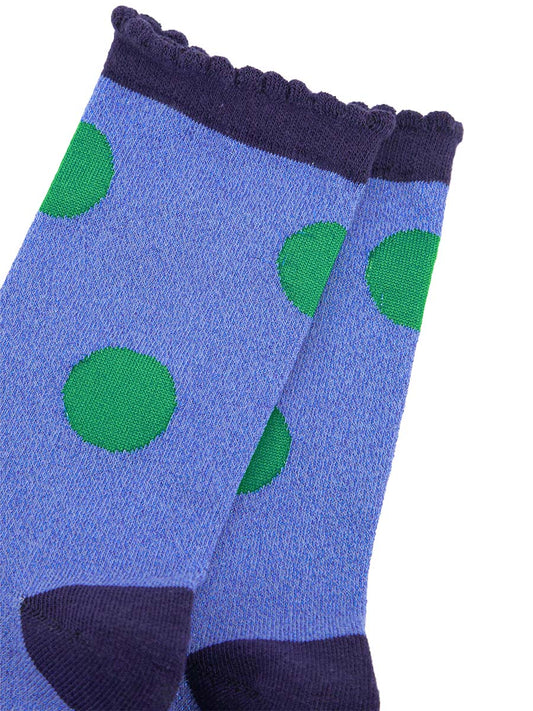 close up of the green polka dot pattern on the denim blue socks