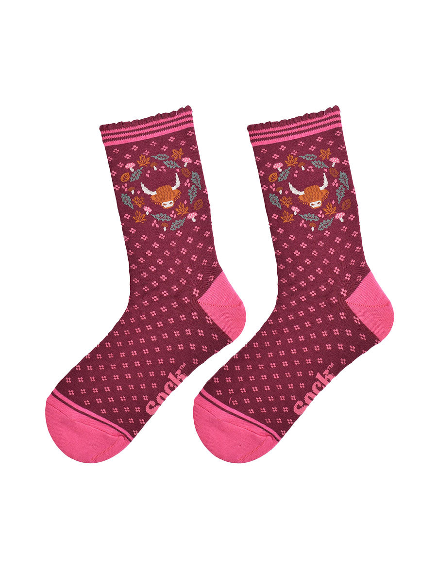 highland cow wreath bamboo socks laying flat, showing burgundy socks with an all over pink floral pattern and a highland cow surrounded by autumn foliage on the ankles