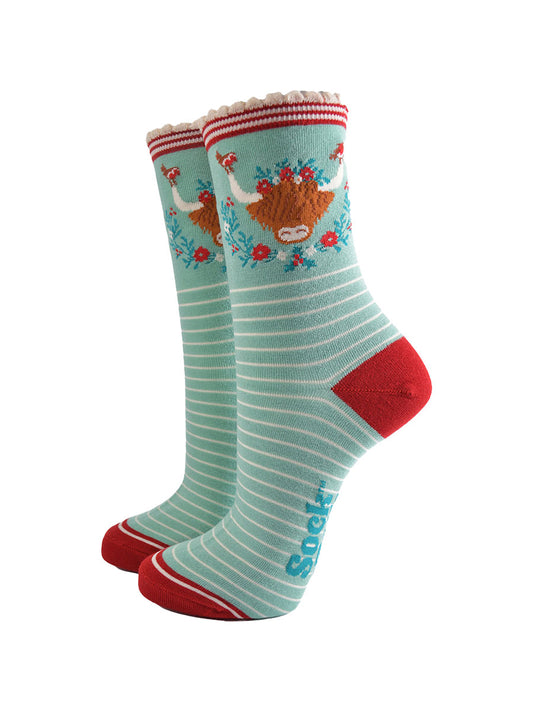 mint green bamboo socks with a large highland cow on the ankle, the highland cow is surrounded by red robin birds, and holly, the socks have a scalloped edge and a white pinstripe