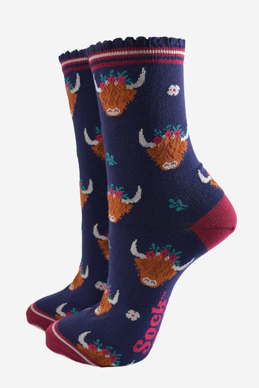 navy blue ankle socks with scalloped cuffs featuring an all over pattern of highland cows wearing winter floral crowns