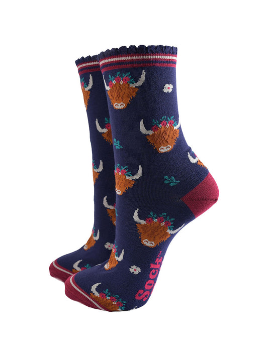 navy blue ankle socks with scalloped cuffs featuring an all over pattern of highland cows wearing winter floral crowns
