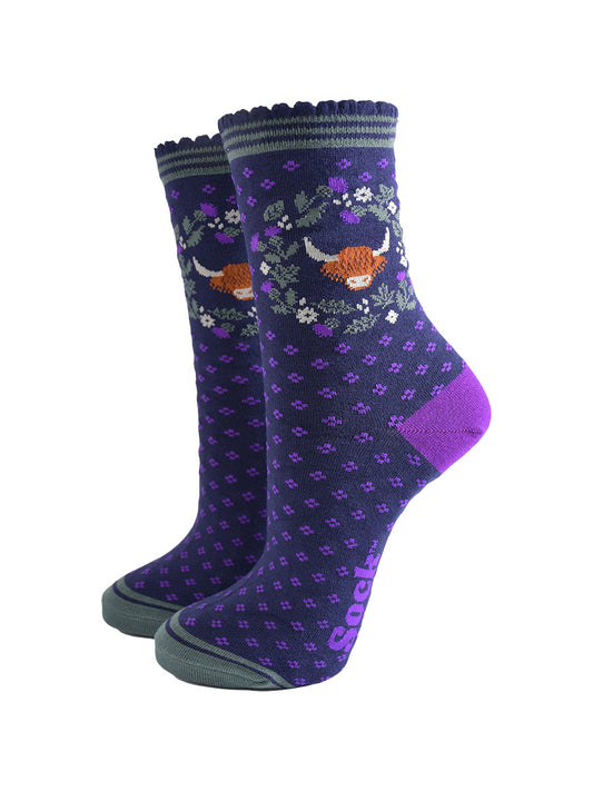 navy blue and purple ankle socks with scalloped cuffs featuring a highland cow and a wreath featuring purple and green scottish thistle flowers