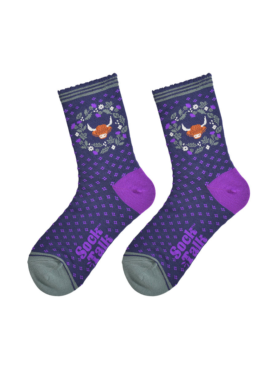 highland cow and wreath bamboo socks laying flat, showing the all over purple spotted pattern, green and purple thistle flower wreath and highland cow