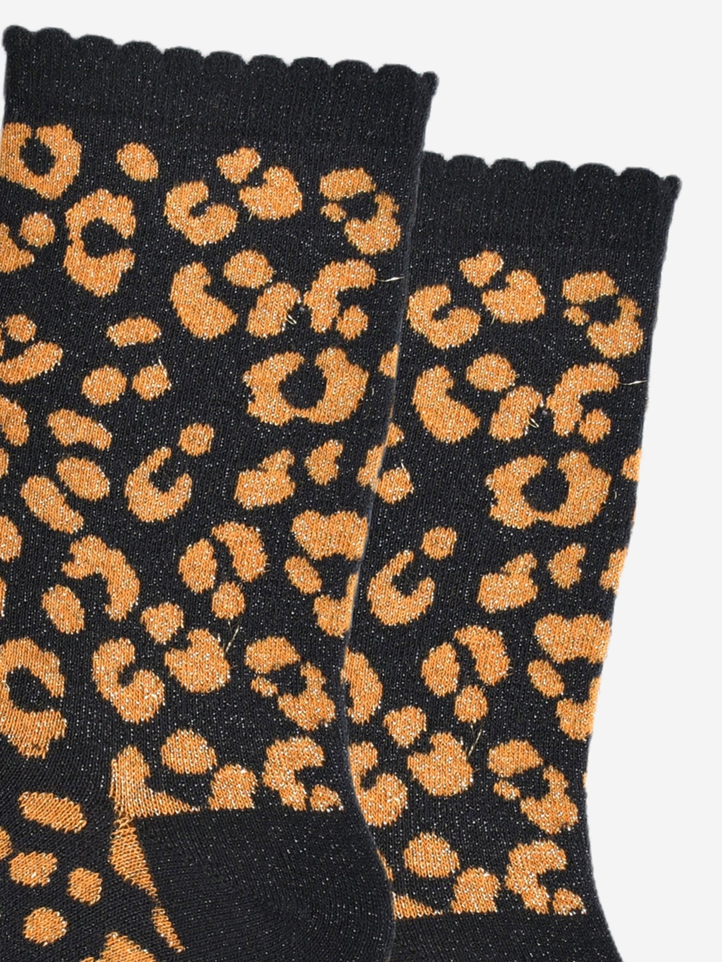 close up of the orange leopard print pattern on the socks, there is a visible silver glitter sparkle all over the design. the pink print contrasts with the black base of the socks