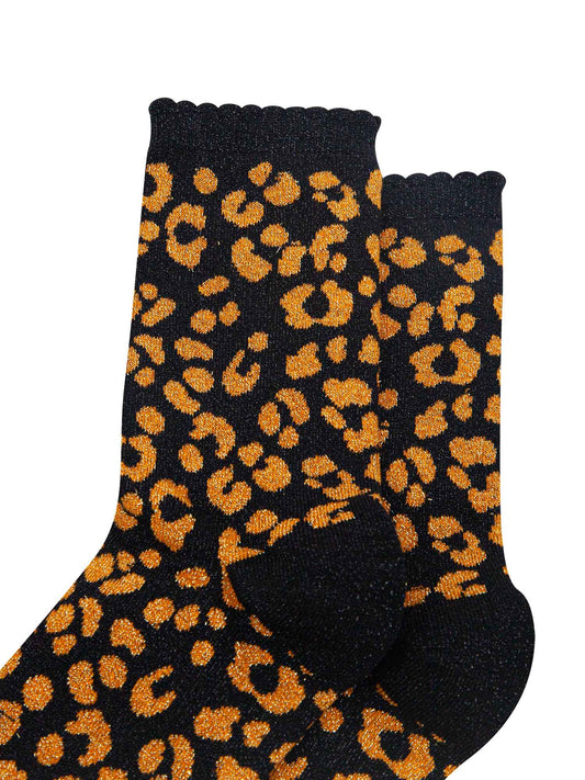close up of the orange leopard print pattern on the socks, there is a visible silver glitter sparkle all over the design. the pink print contrasts with the black base of the socks