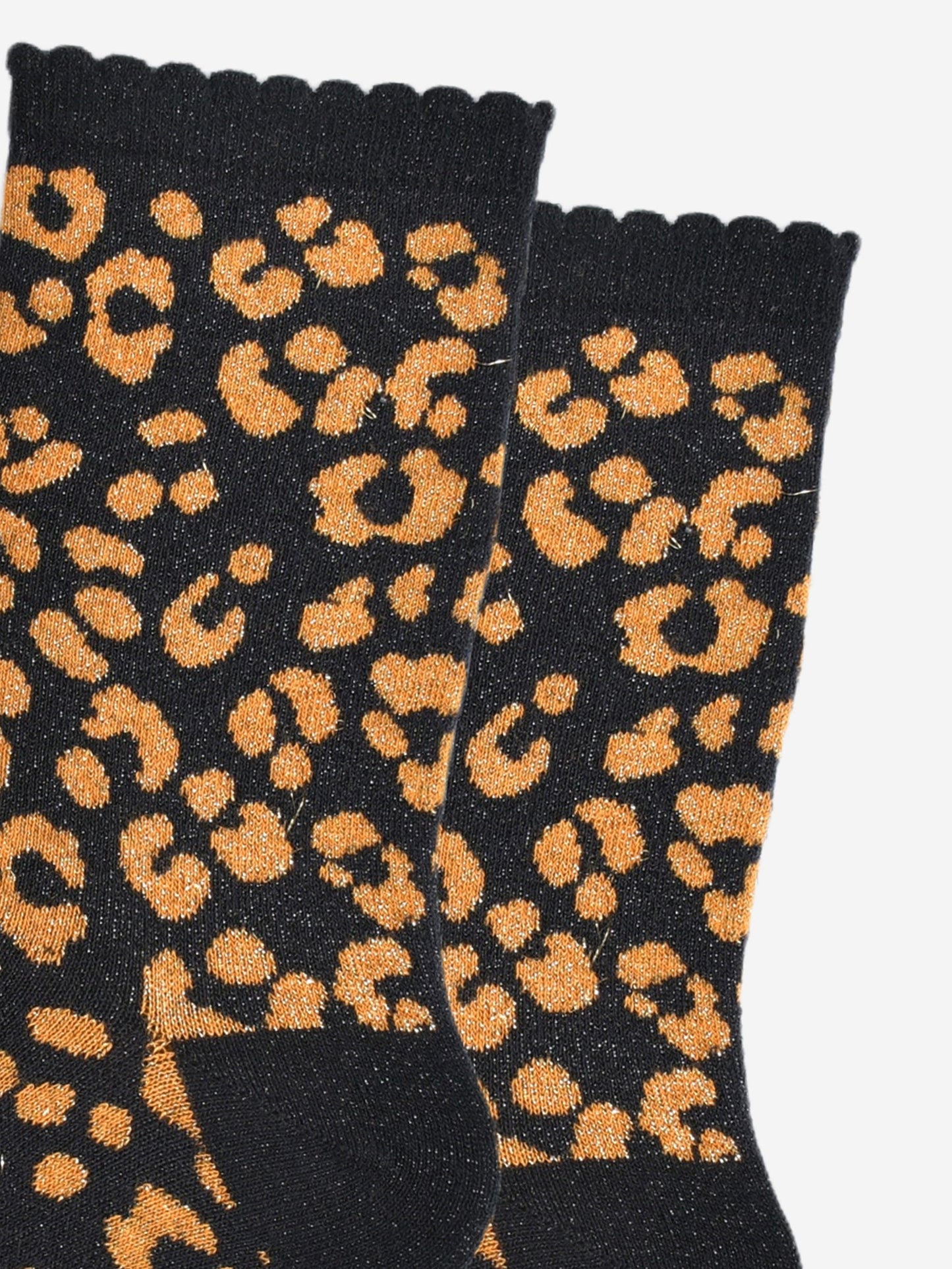 close up of the orange leopard print pattern on the socks, there is a visible silver glitter sparkle all over the design. the pink print contrasts with the black base of the socks