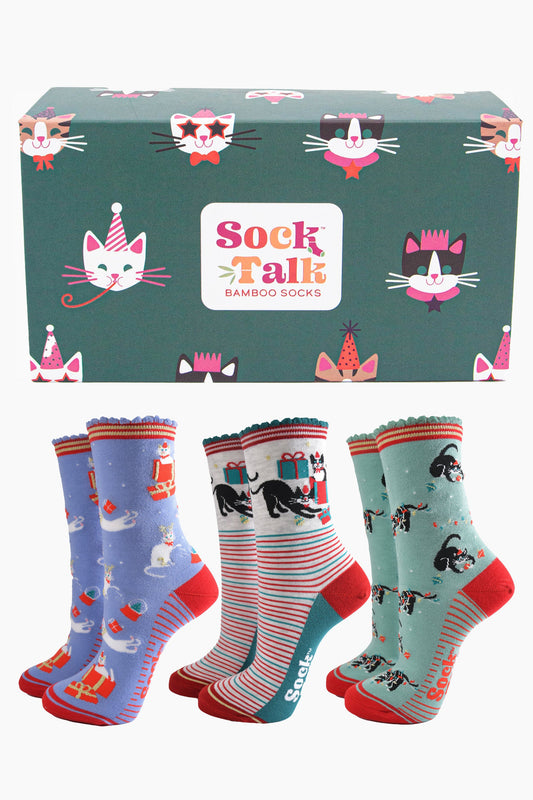 a green gift box adorned with cats wearing party hats and three pairs of festive inspired cat socks