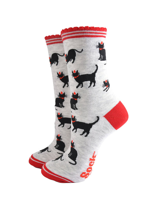 light grey socks with black cats wearing festive party hats, the socks have red striped scalloped cuffs, red toe and heel