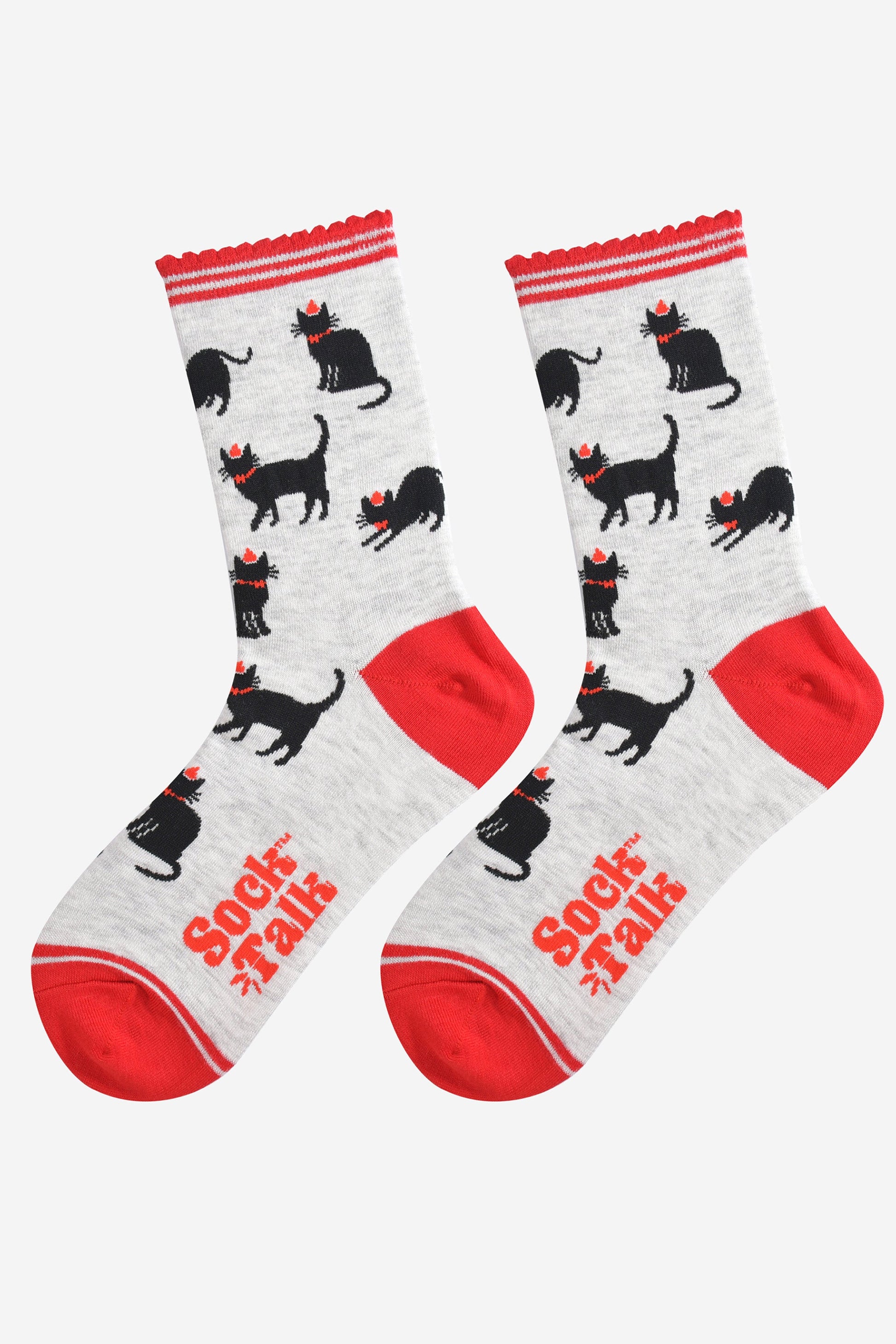 showing the black cat socks laying flat, highlighting the all over pattern of sitting, strutting and stretching cats, each wearing a red party hat and bow tie