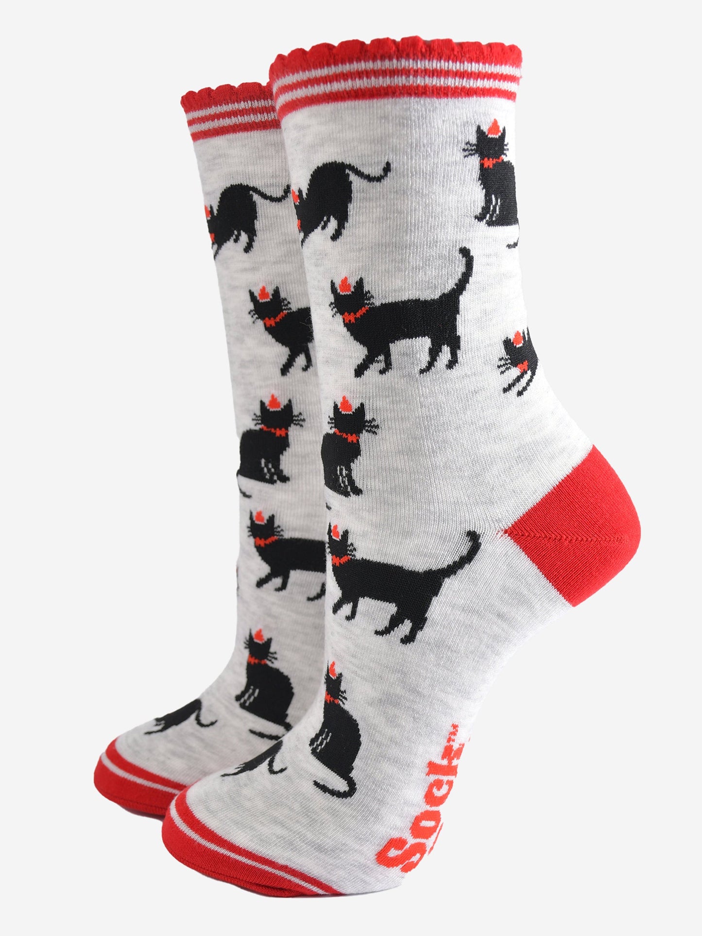 light grey socks with black cats wearing festive party hats, the socks have red striped scalloped cuffs, red toe and heel