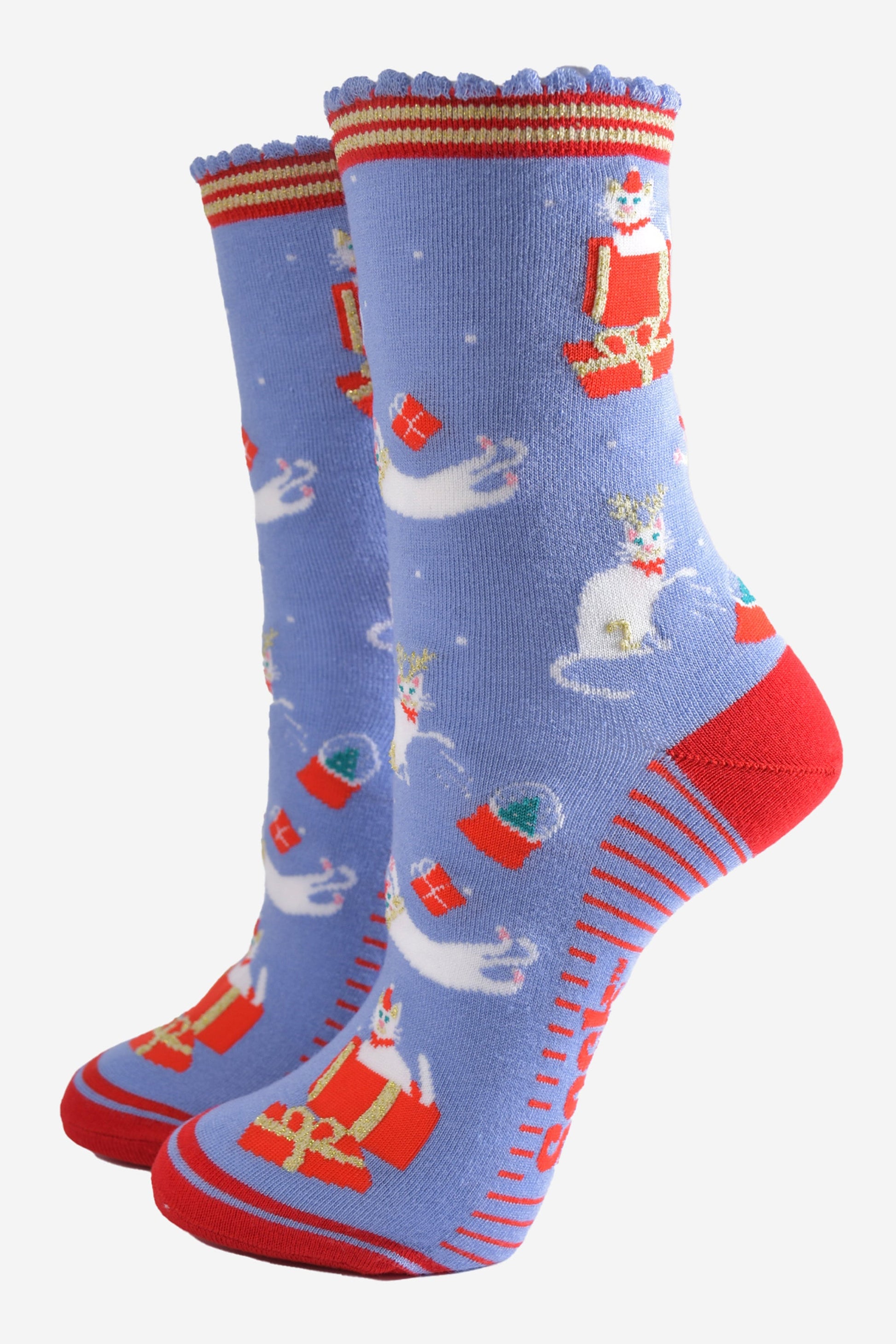 light blue socks with a contrasting red heel, toe and striped cuff and sole with a pattern of white cats playing with snow globes and christmas presents