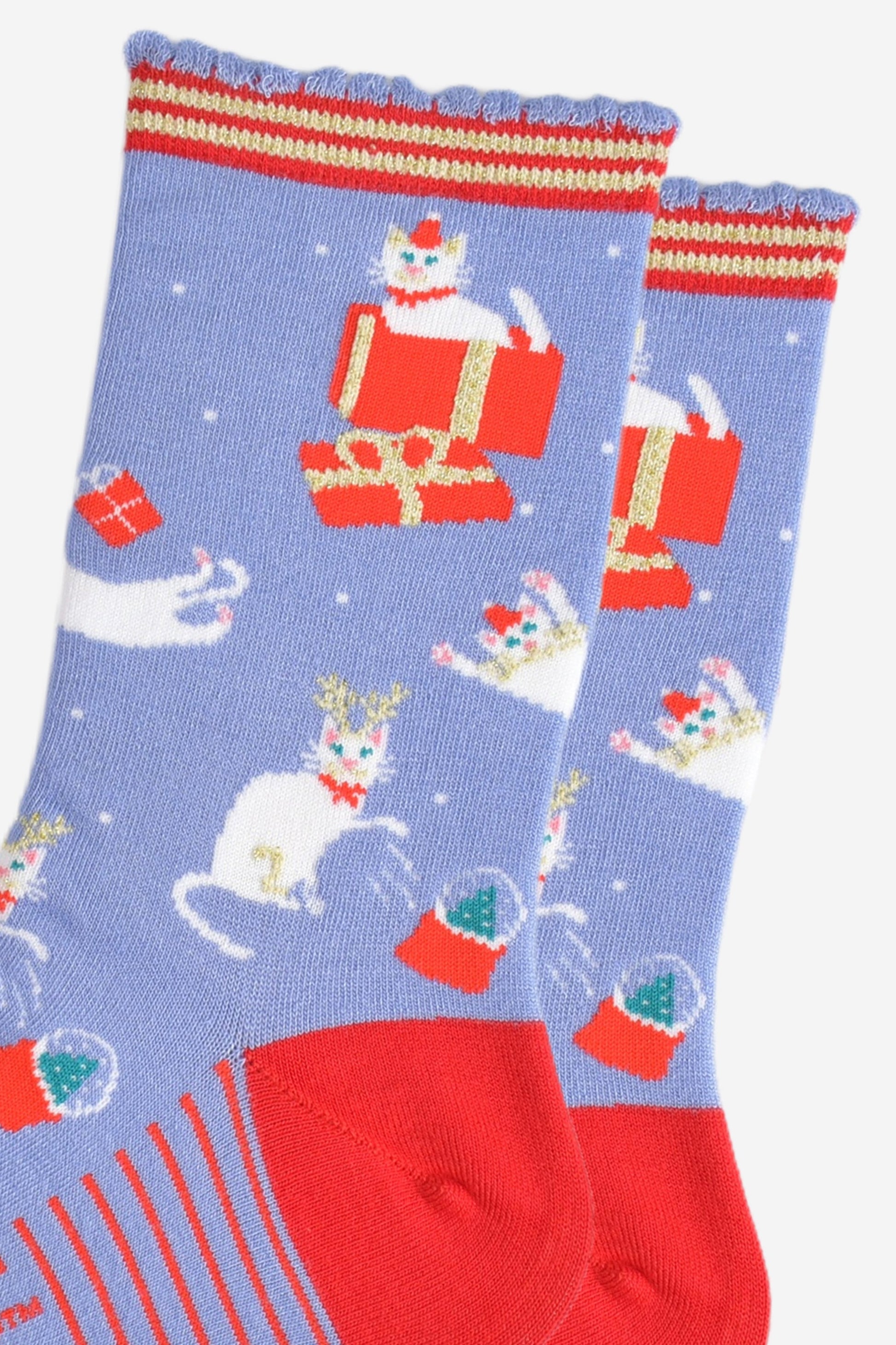 close up of the white cats on the socks, they are sitting inside gift boxes, playing with presents and pawing at snow globes