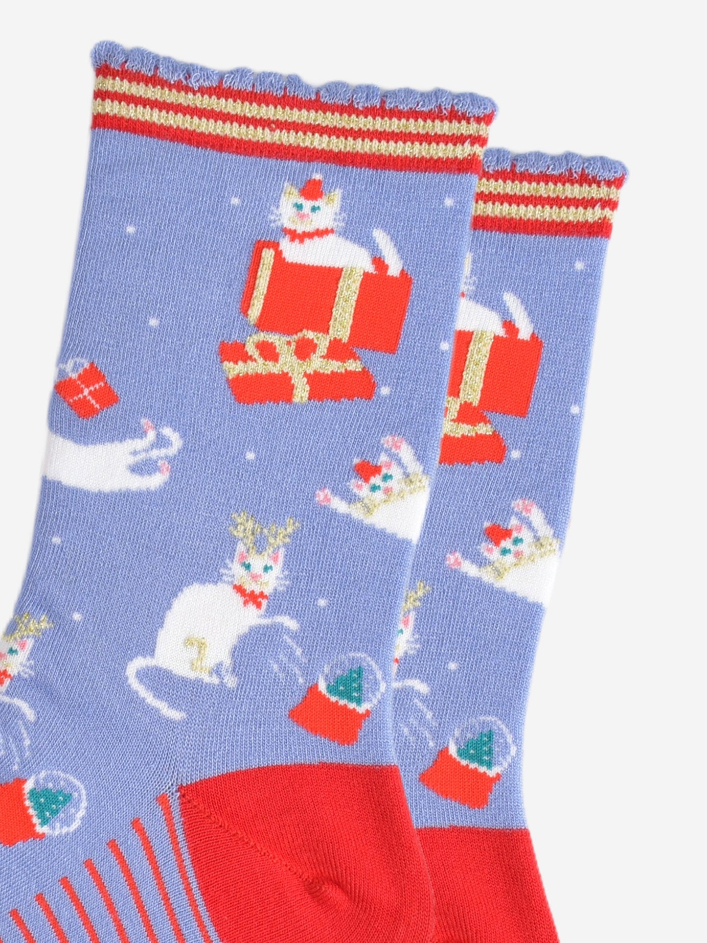 close up of the white cats on the socks, they are sitting inside gift boxes, playing with presents and pawing at snow globes