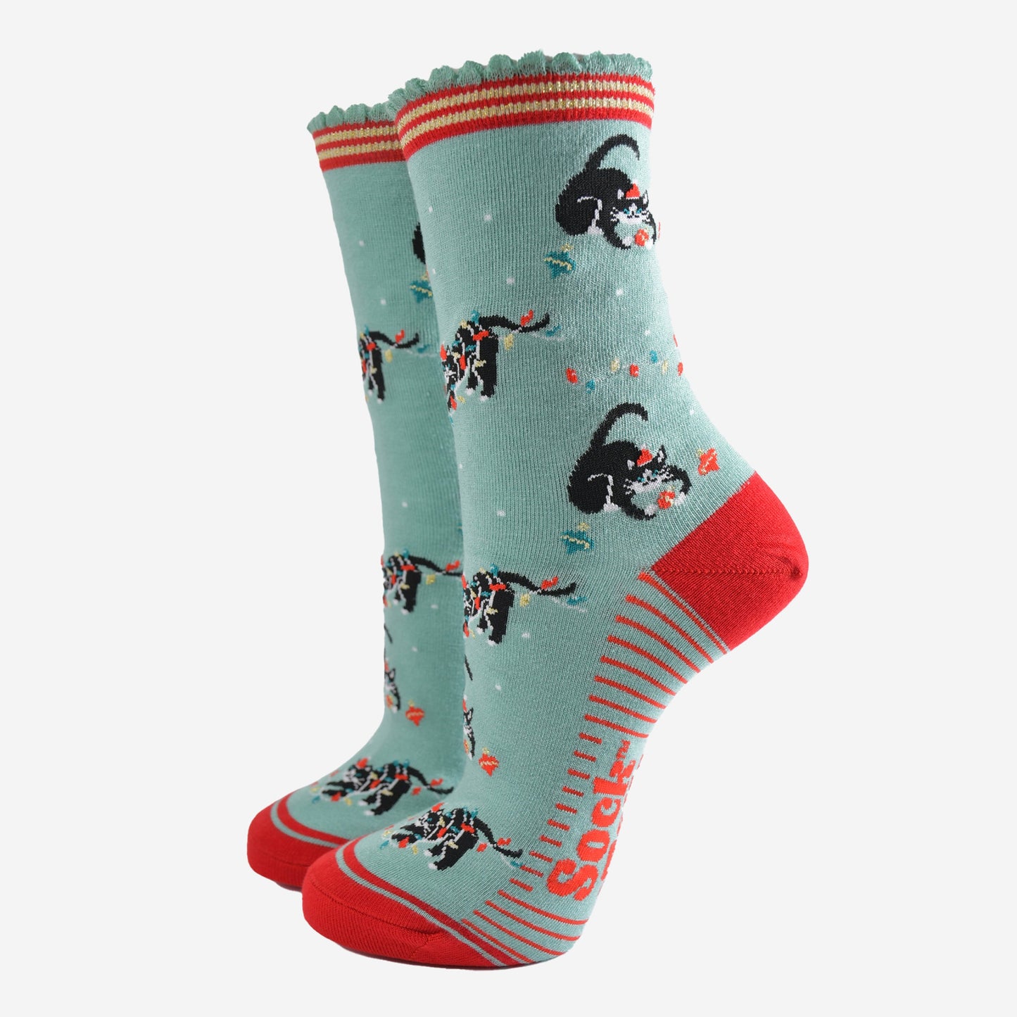 mint green socks with a red heel, toe and striped sole with a pattern of black cats playing with christmas lights and baubles