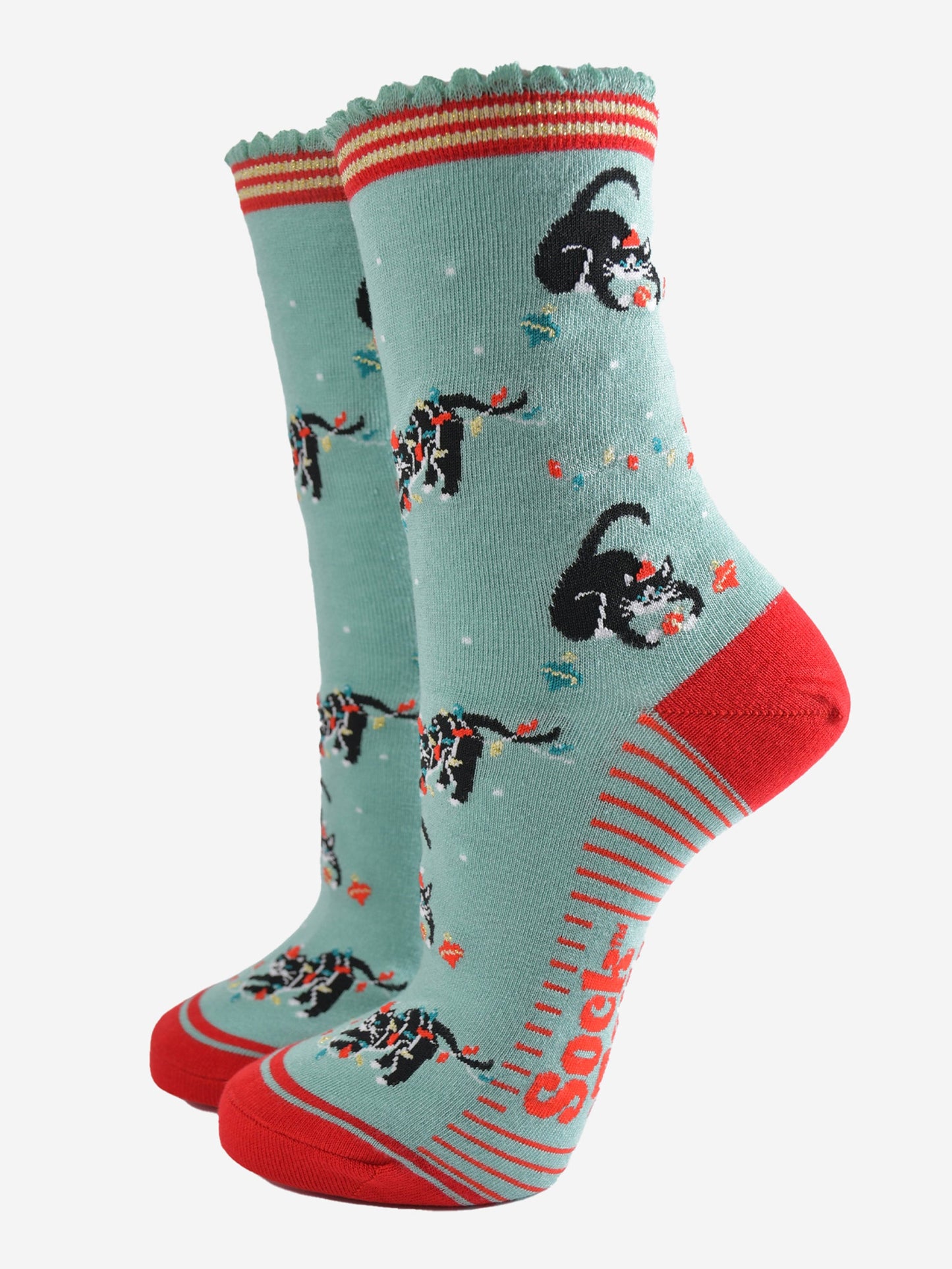 mint green socks with a red heel, toe and striped sole with a pattern of black cats playing with christmas lights and baubles