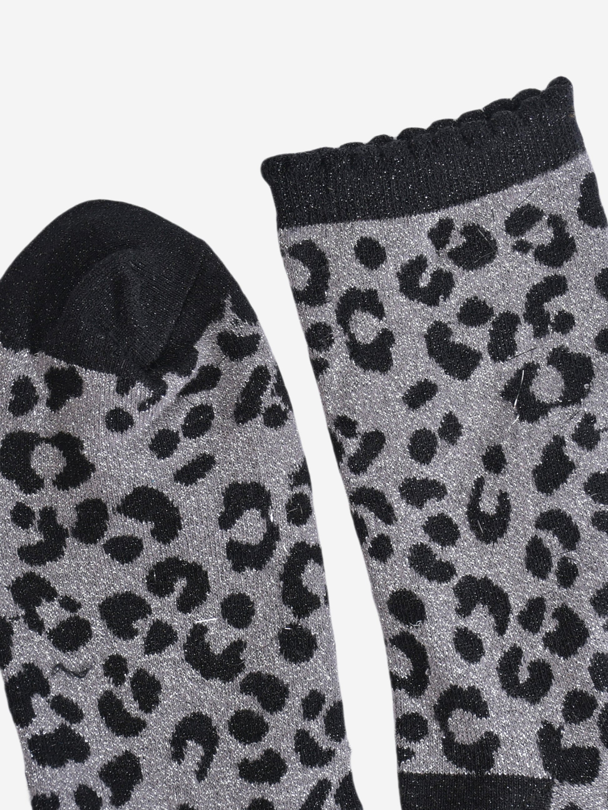 showing the toe and cuff of the socks, the toe is black and sparkly like the black leopard print pattern, the cuff is also black and sparkly and has a scalloped edge