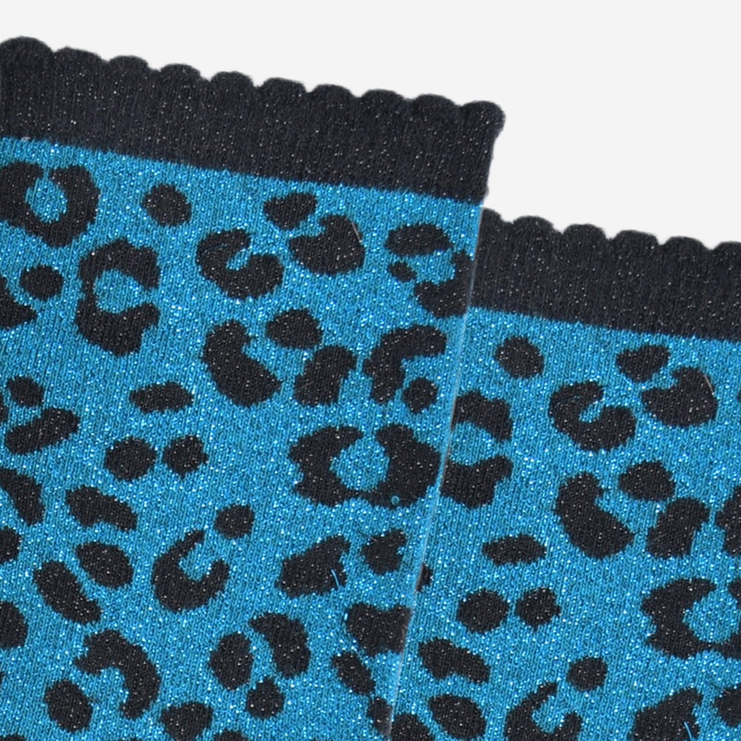 close up of the teal leopard print pattern on the socks, there is a visible silver glitter sparkle all over the design. the teal blue print contrasts with the black base of the socks