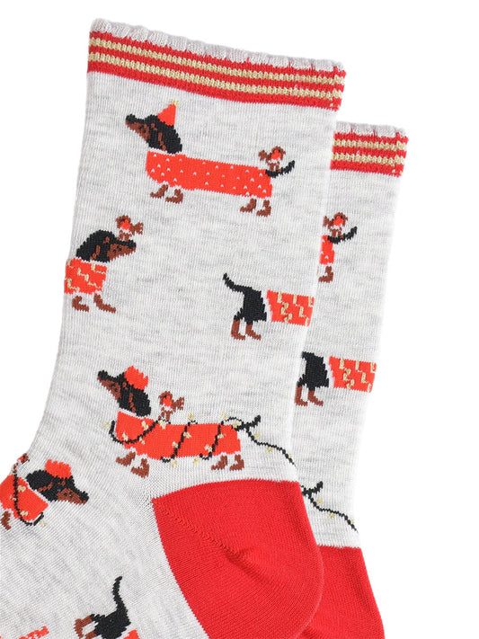 close up of the sausage dog pattern, the dogs are black and wearing red coats. one dog is wearing a red party hat and has a robin on its back. one dog is wrapped in gold party lights and is wearing a red party crown, also with a robin on its back. the last design is a dog wearing a red and gold coat and has a robin sitting on its nose.