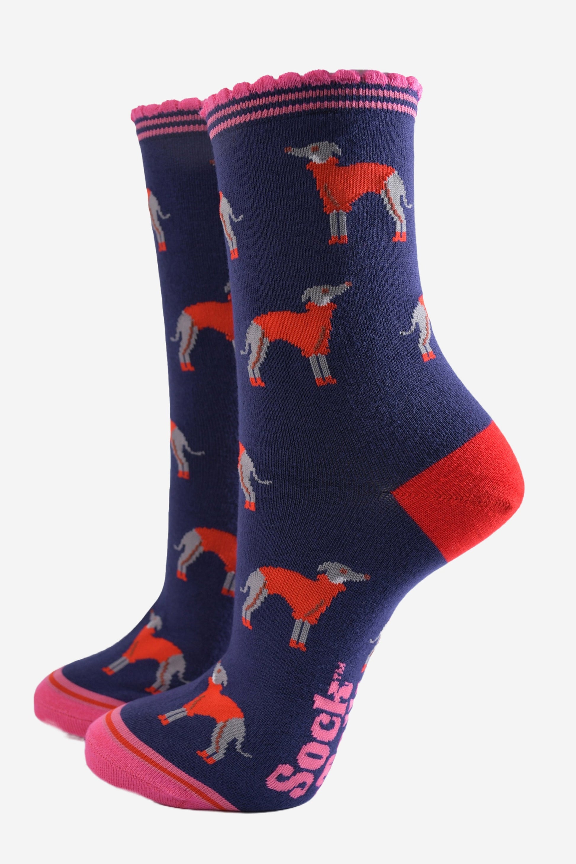 navy blue ankle socks with a pink scalloped cuff, with a pattern of greyhound dogs wearing cosy red knitted jumpers