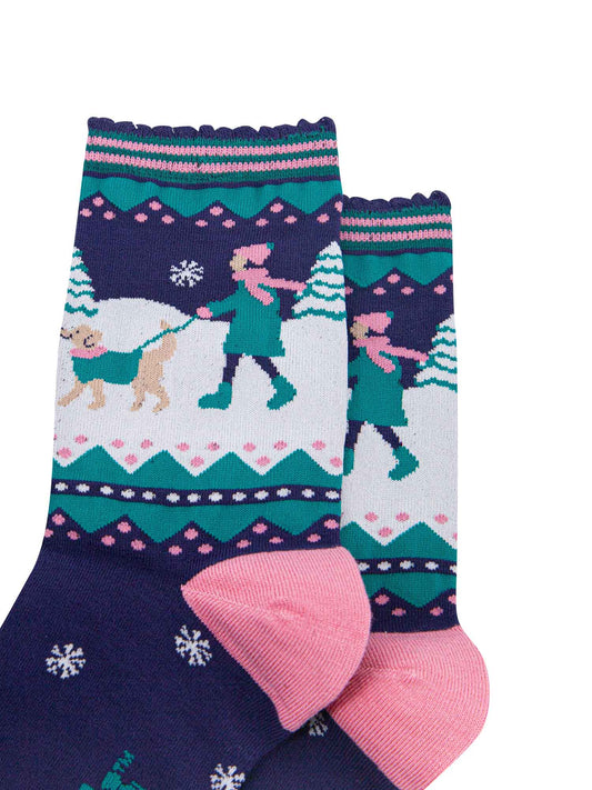 navy blue, pink and teal ankle socks featuring a snowy winter scene with a golden retriever dog taking its owner for a walk
