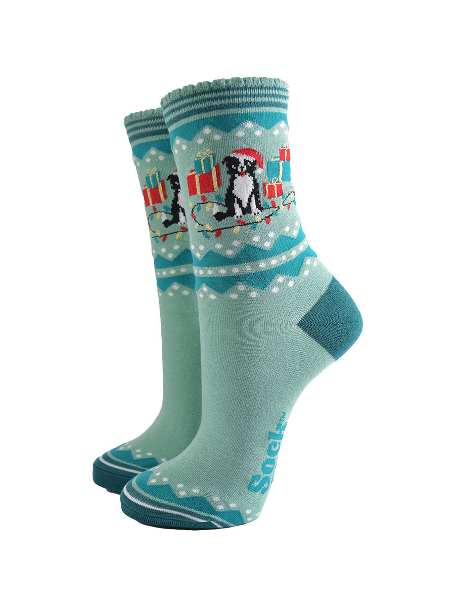 mint green ankle socks with a border collie dog surrounded by christmas presents and party lights, the dog is wearing a santa hat