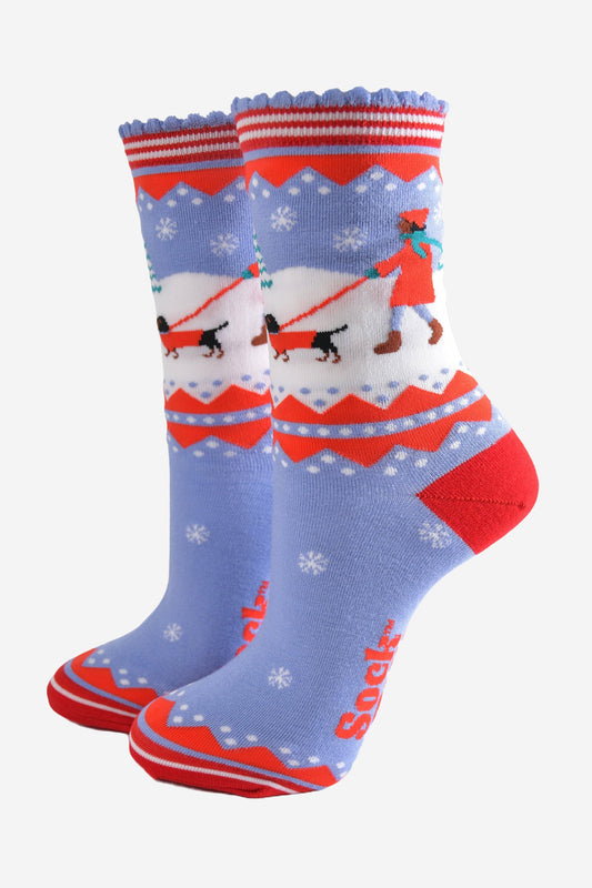 blue and red bamboo socks with a winter scene, showing a sausage dog and its owner taking a walk in the snow. 