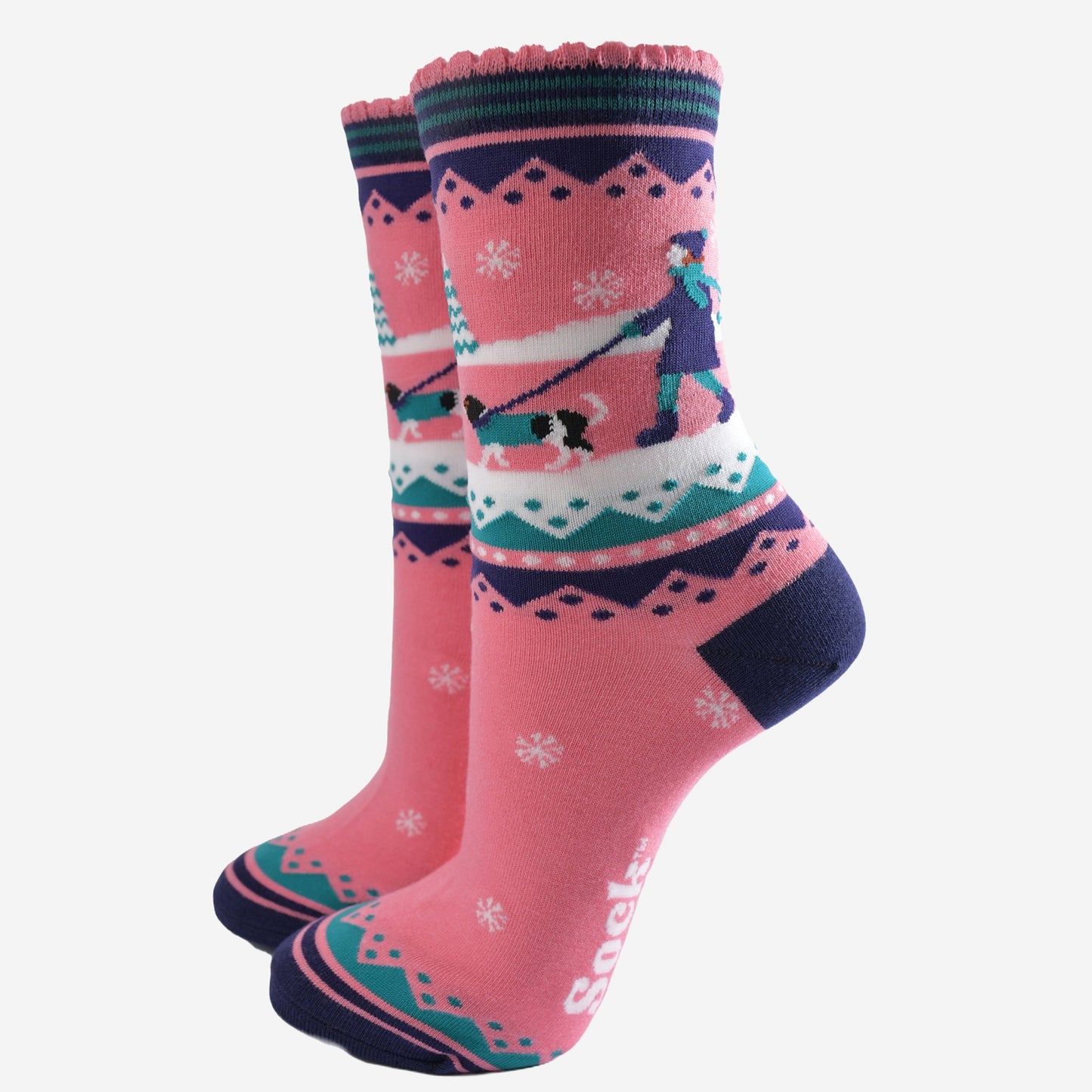 pink ankle socks with blue and green accents, showing a snowy winter scene with a woman walking a king charles spaniel