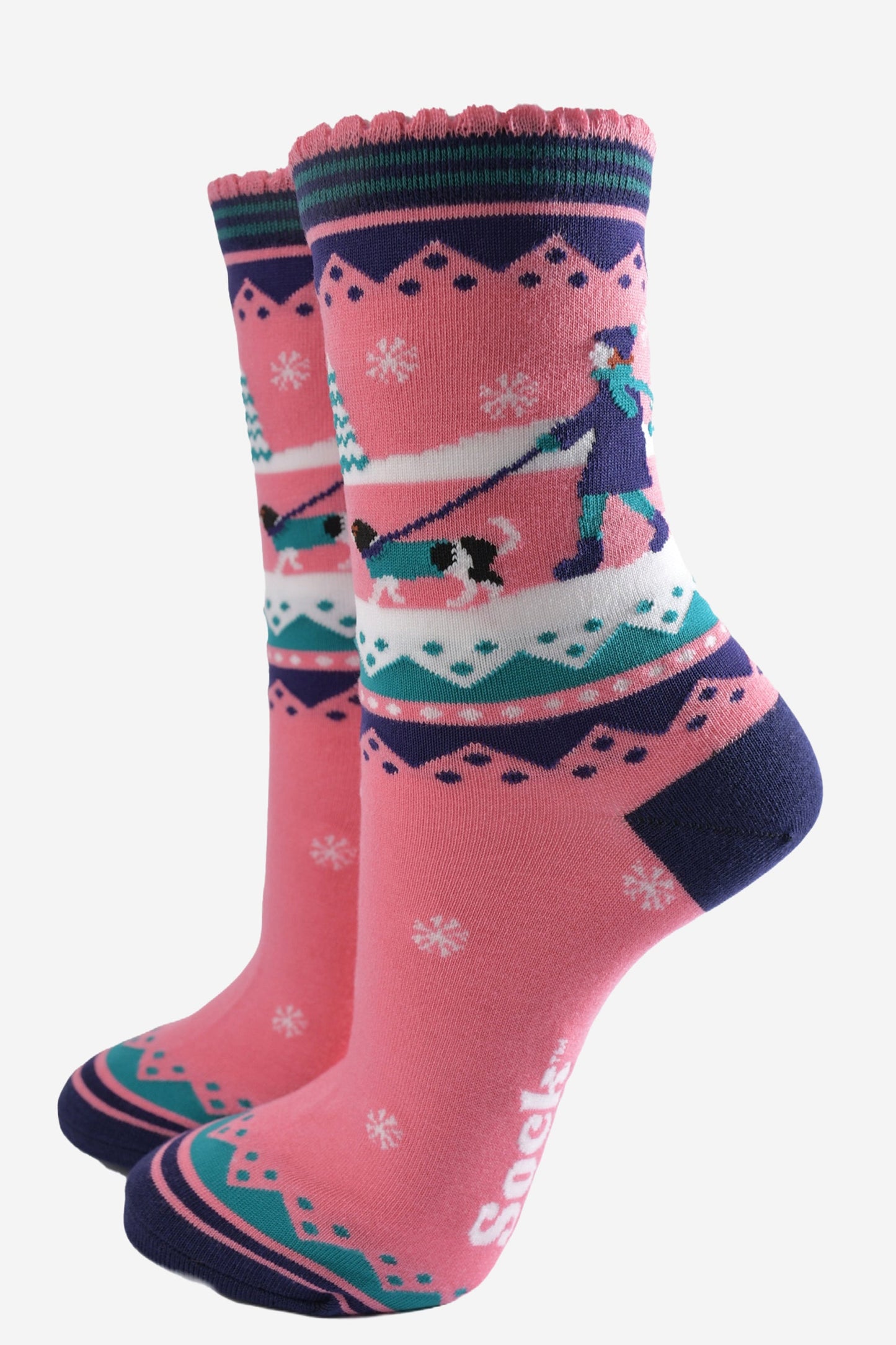 pink ankle socks with blue and green accents, showing a snowy winter scene with a woman walking a king charles spaniel