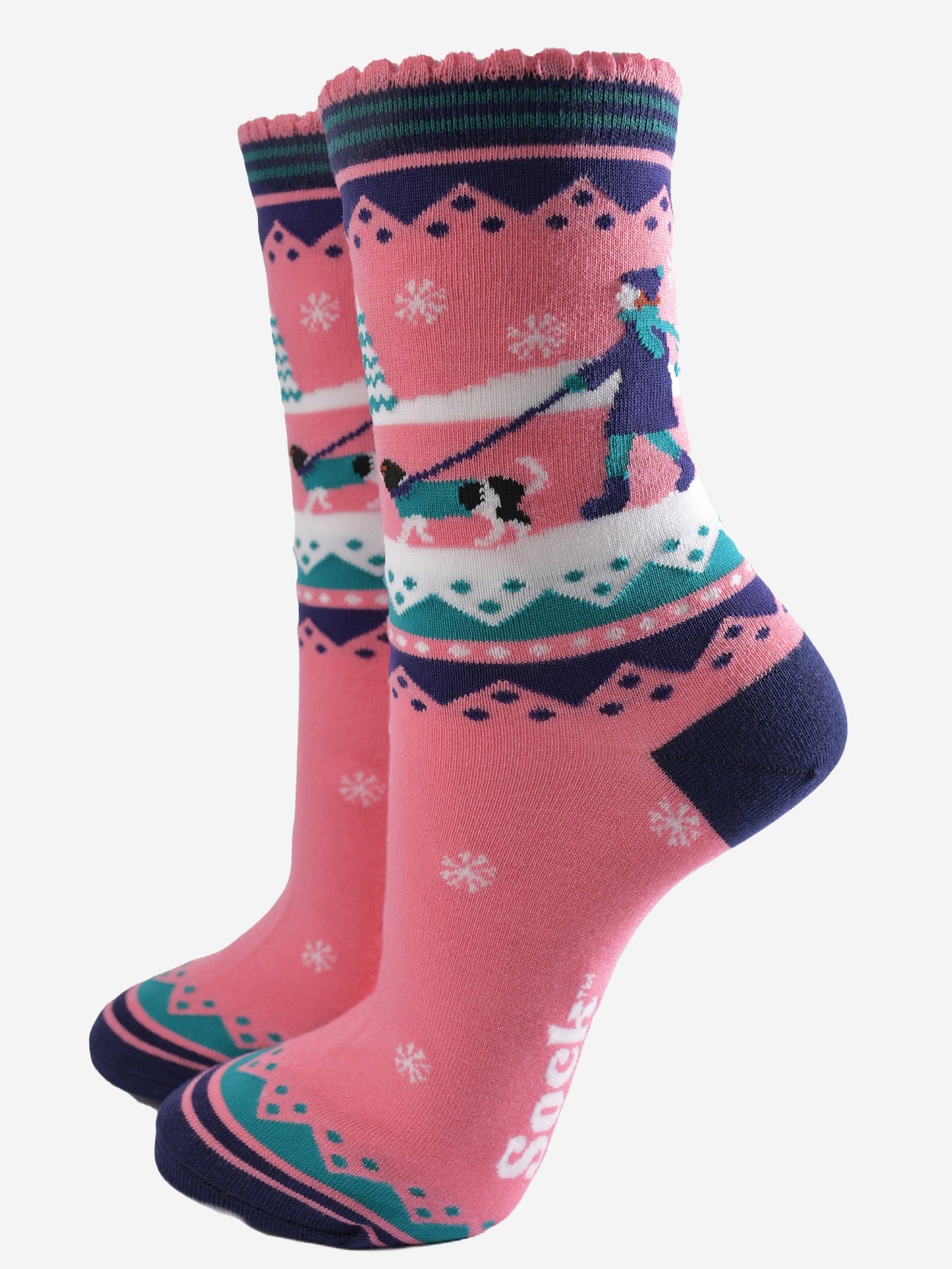 pink ankle socks with blue and green accents, showing a snowy winter scene with a woman walking a king charles spaniel