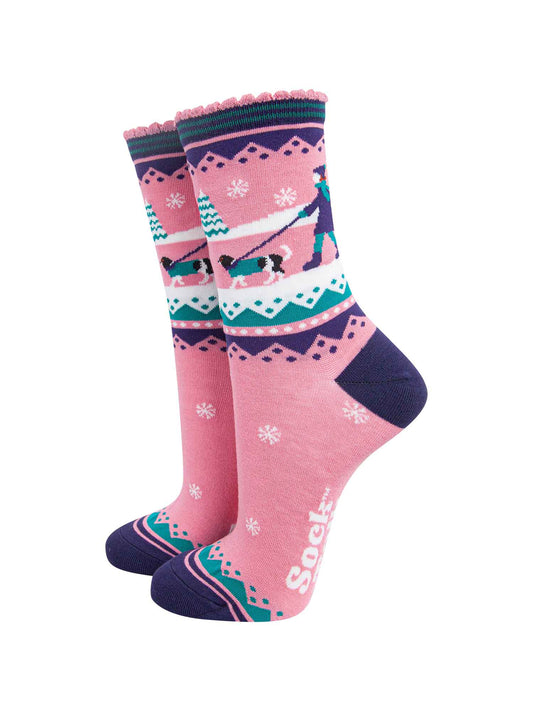 pink ankle socks with blue and green accents, showing a snowy winter scene with a woman walking a king charles spaniel