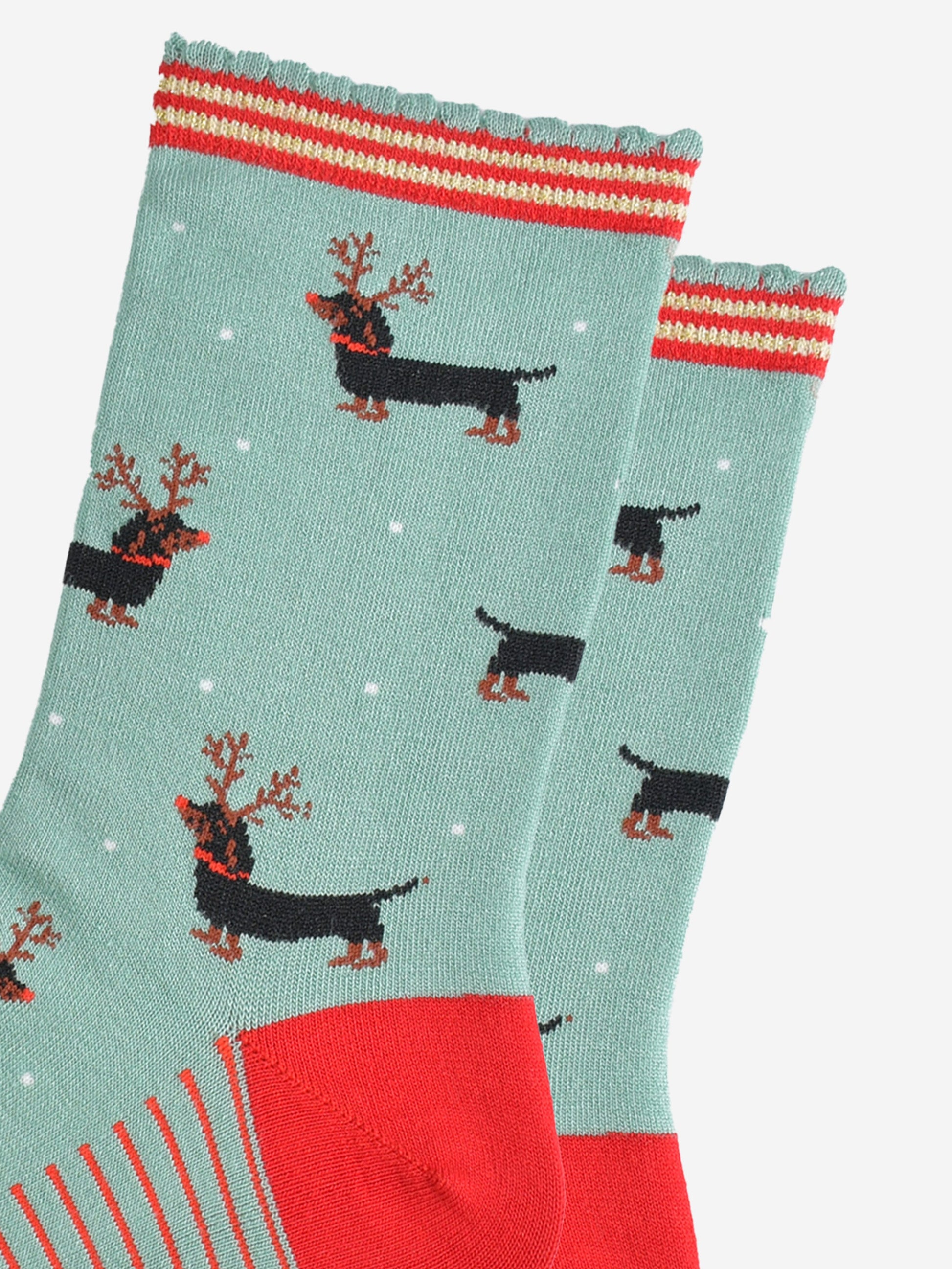 close up of the sausage dog pattern, the dogs are black and tan, traditional markings, they are wearing a set of brown reindeer antlers and wearing red noses like rudolph.
