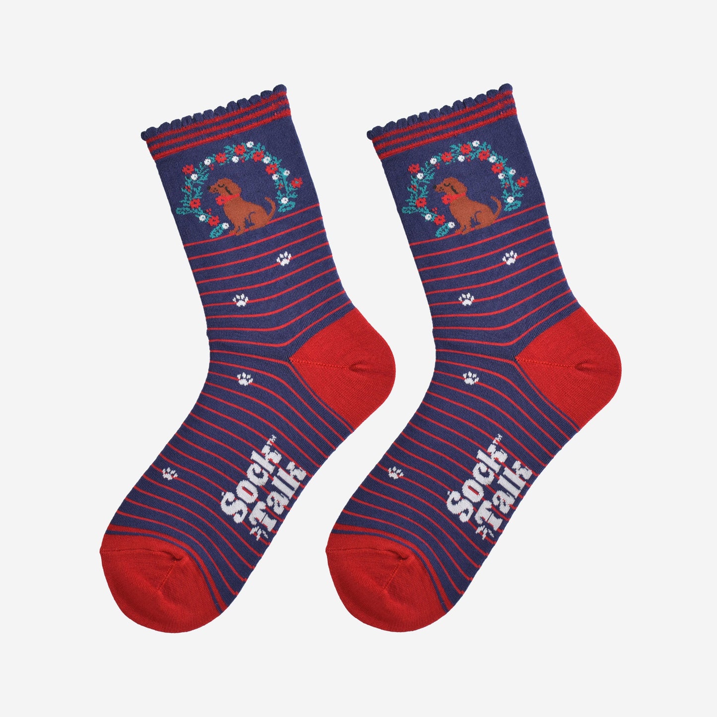 showing the socks laying flat, there is a red horizontal pinstripe throughout the socks except for the ankle where the sausage dog and wreath and located, there are white paw prints on the socks aswell