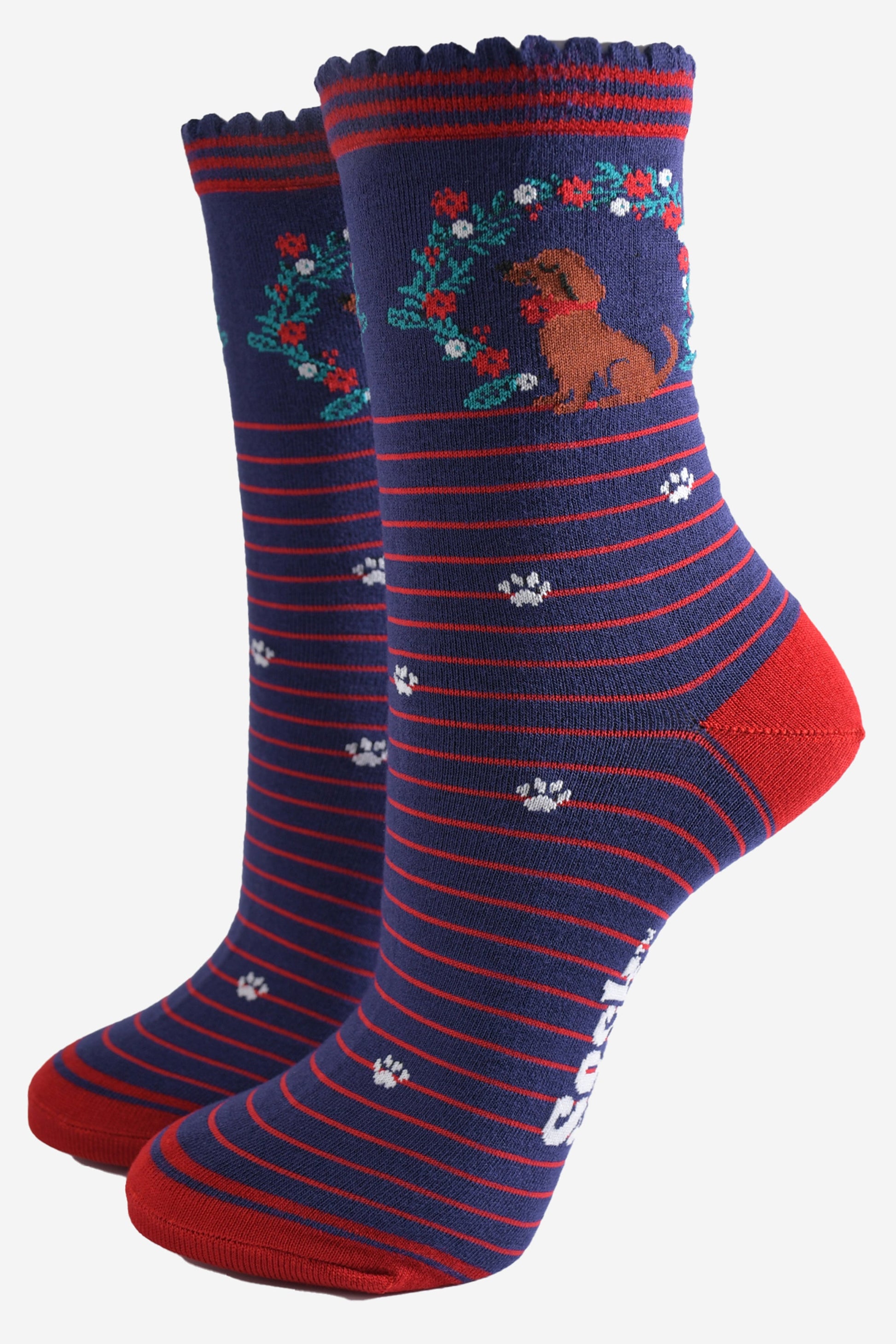 navy blue socks with red stripes, featuring a playful sausage dog and seasonal floral wreath