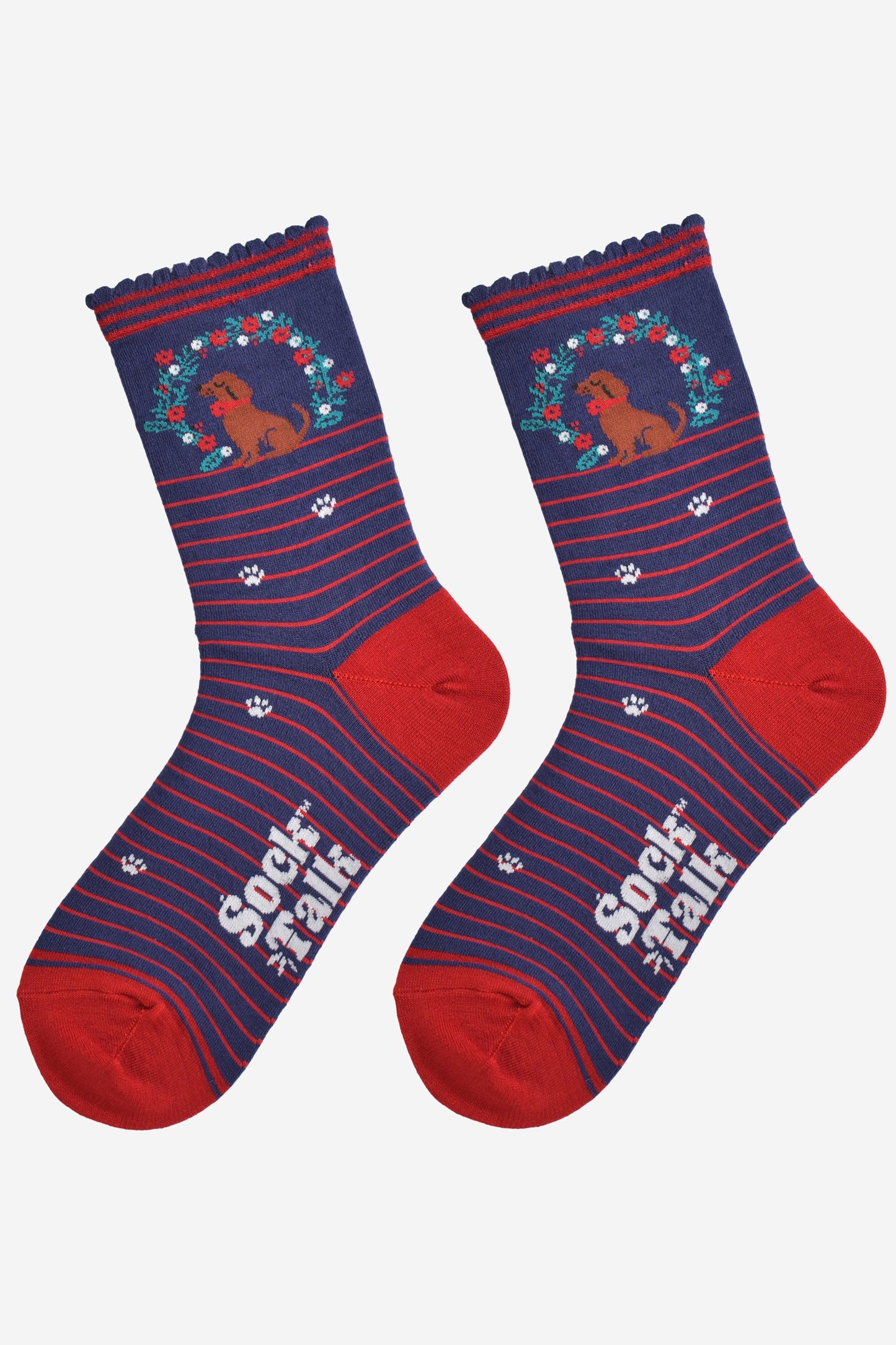 showing the socks laying flat, there is a red horizontal pinstripe throughout the socks except for the ankle where the sausage dog and wreath and located, there are white paw prints on the socks aswell