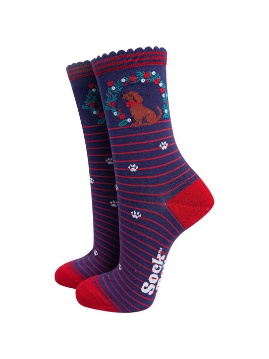 navy blue socks with red stripes, featuring a playful sausage dog and seasonal floral wreath