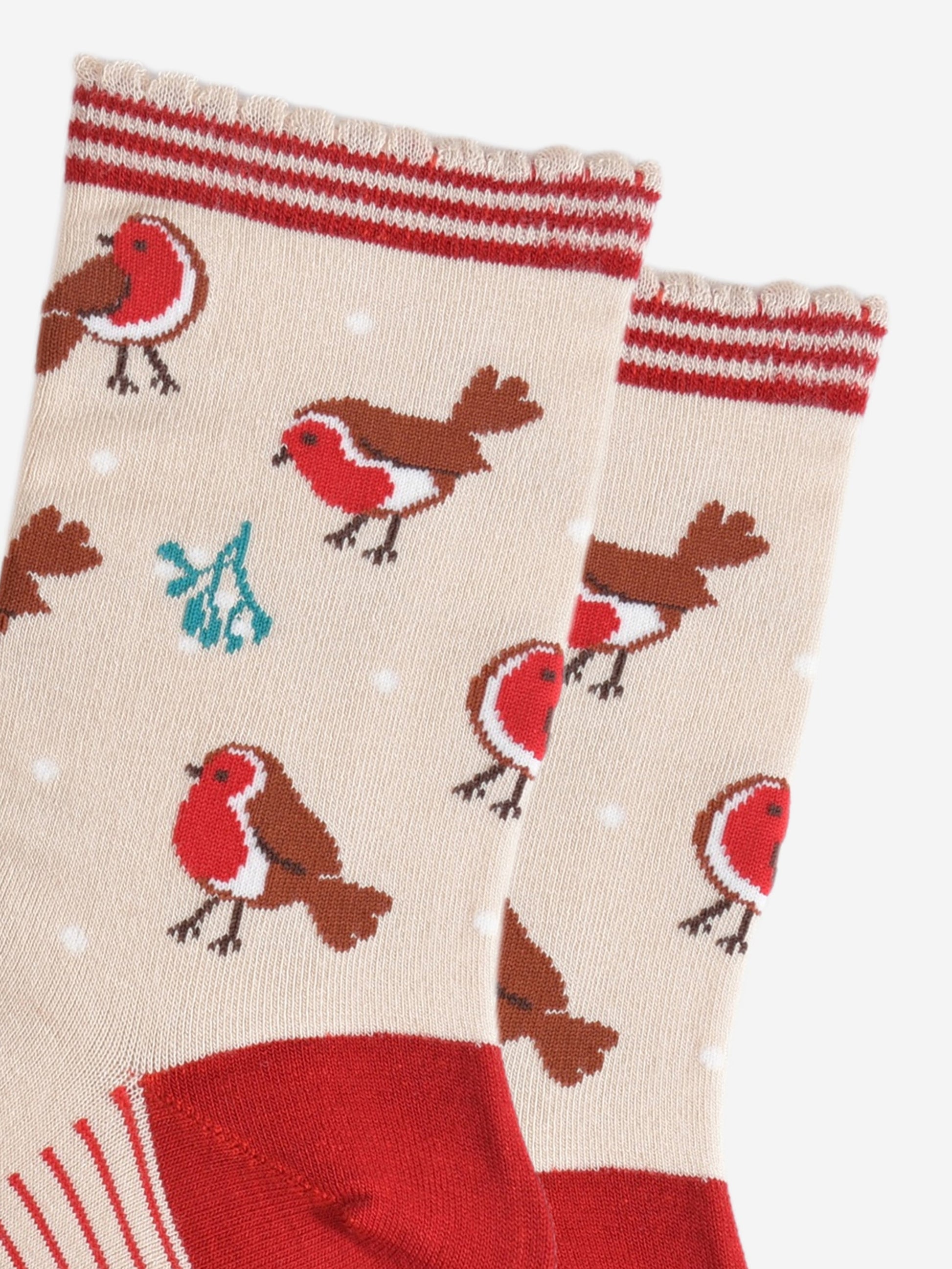 close up of the red robins and mistle toe pattern on the socks, also visible are small white dots designed to look like subtle falling snowflakes