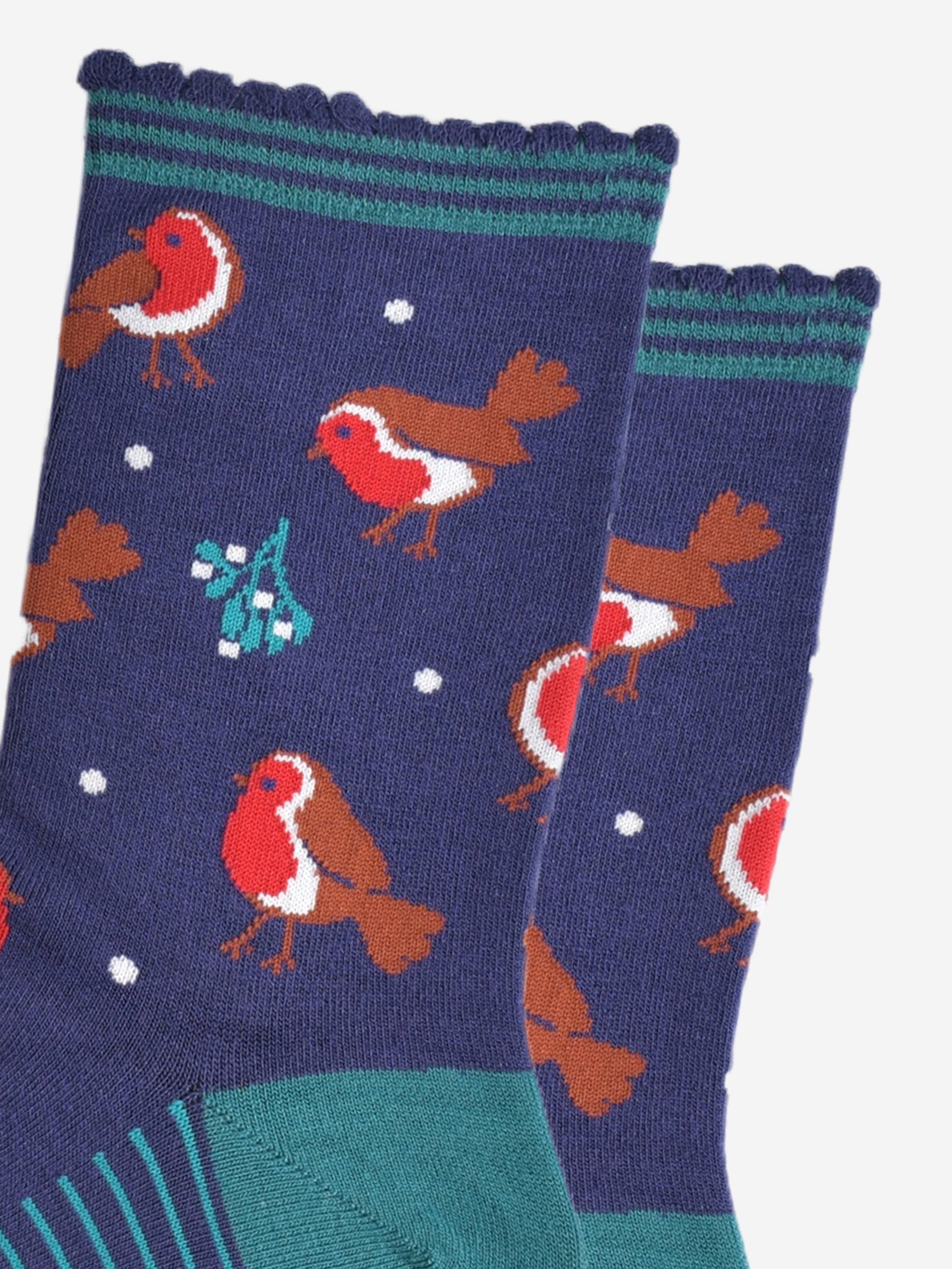 close up of the red robins and mistle toe pattern on the socks, also visible are small white dots designed to look like subtle falling snowflakes