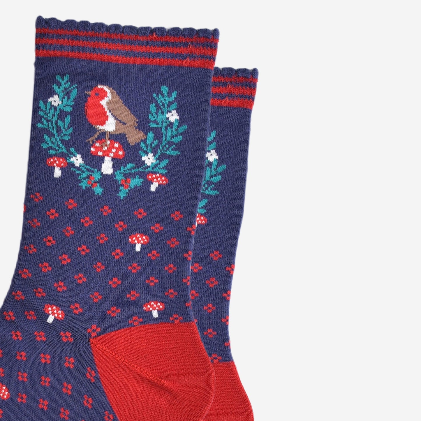 close up of the red robin and festive holly wreath on the ankle of the socks, the robin is perched on a red toadstool in the centre of the wreath, the wreath is horseshoe shaped and does not fully enclose the robin