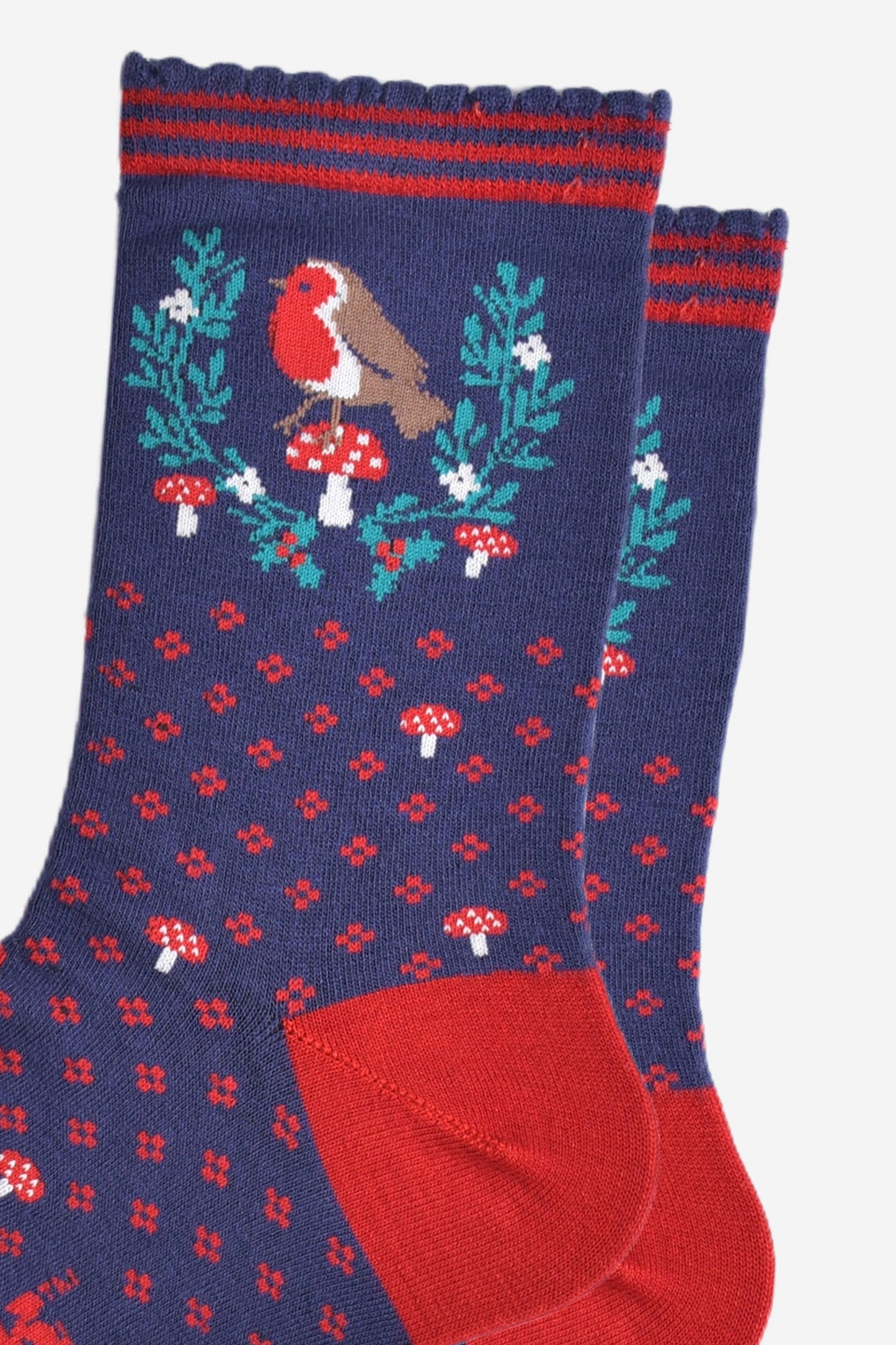 close up of the red robin and festive holly wreath on the ankle of the socks, the robin is perched on a red toadstool in the centre of the wreath, the wreath is horseshoe shaped and does not fully enclose the robin