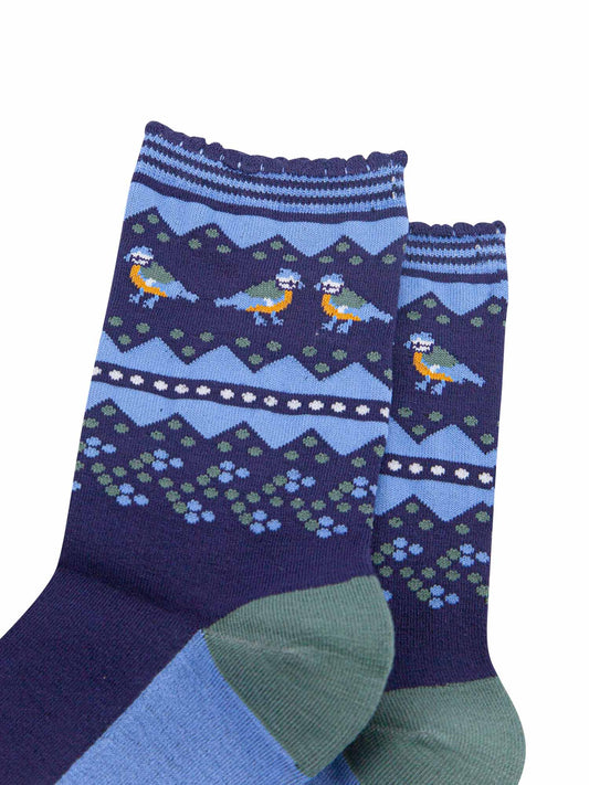close up of the fair isle pattern and blue tit birds on the ankles of the socks, the birds are in pairs and are facing each other, they are yellow, blue and green 
