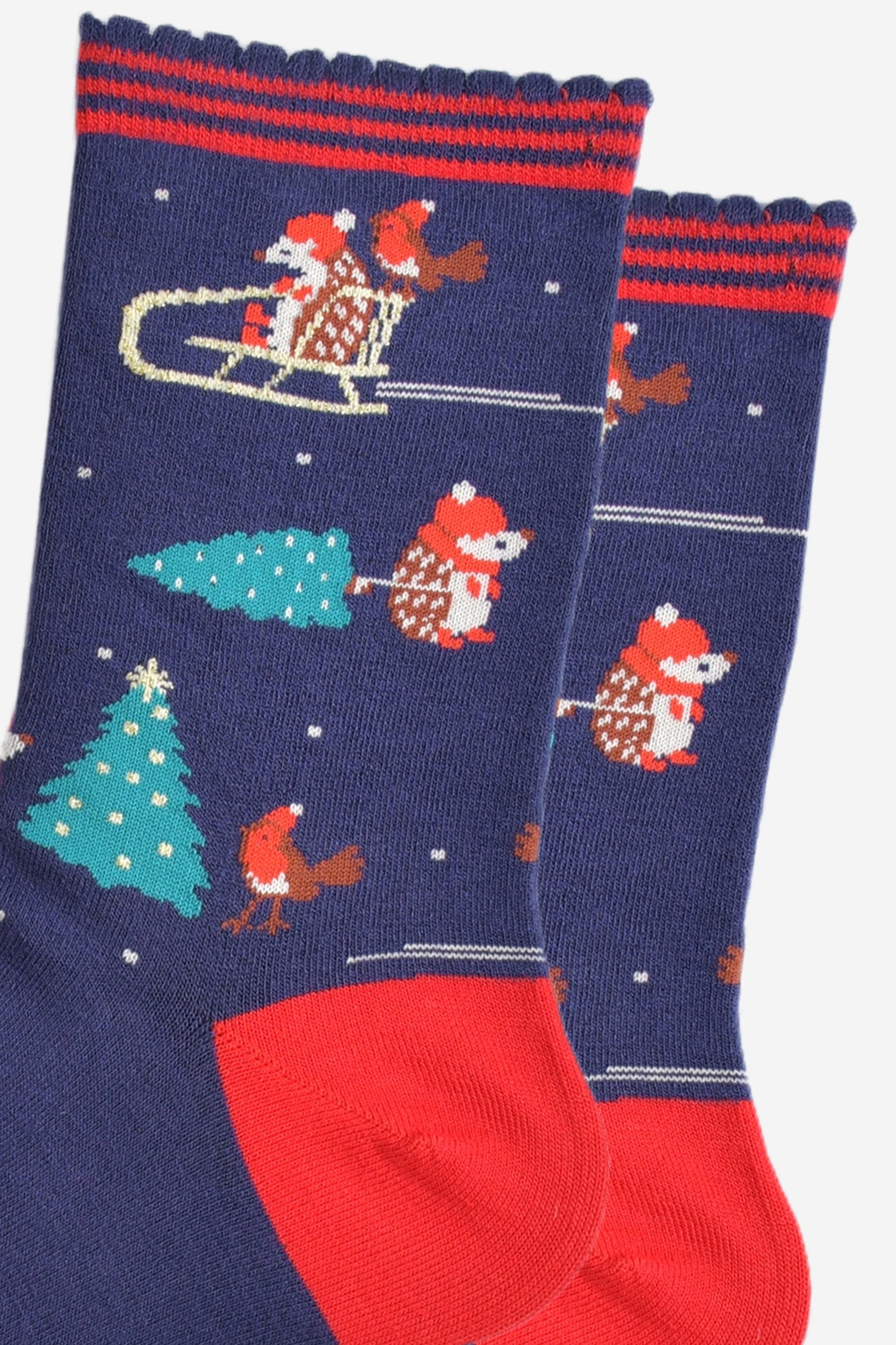 close up of the hedgehog and robin bird design on the socks, there is a hedgehog and robin on a sledge and a hedgehog pulling a xmas tree